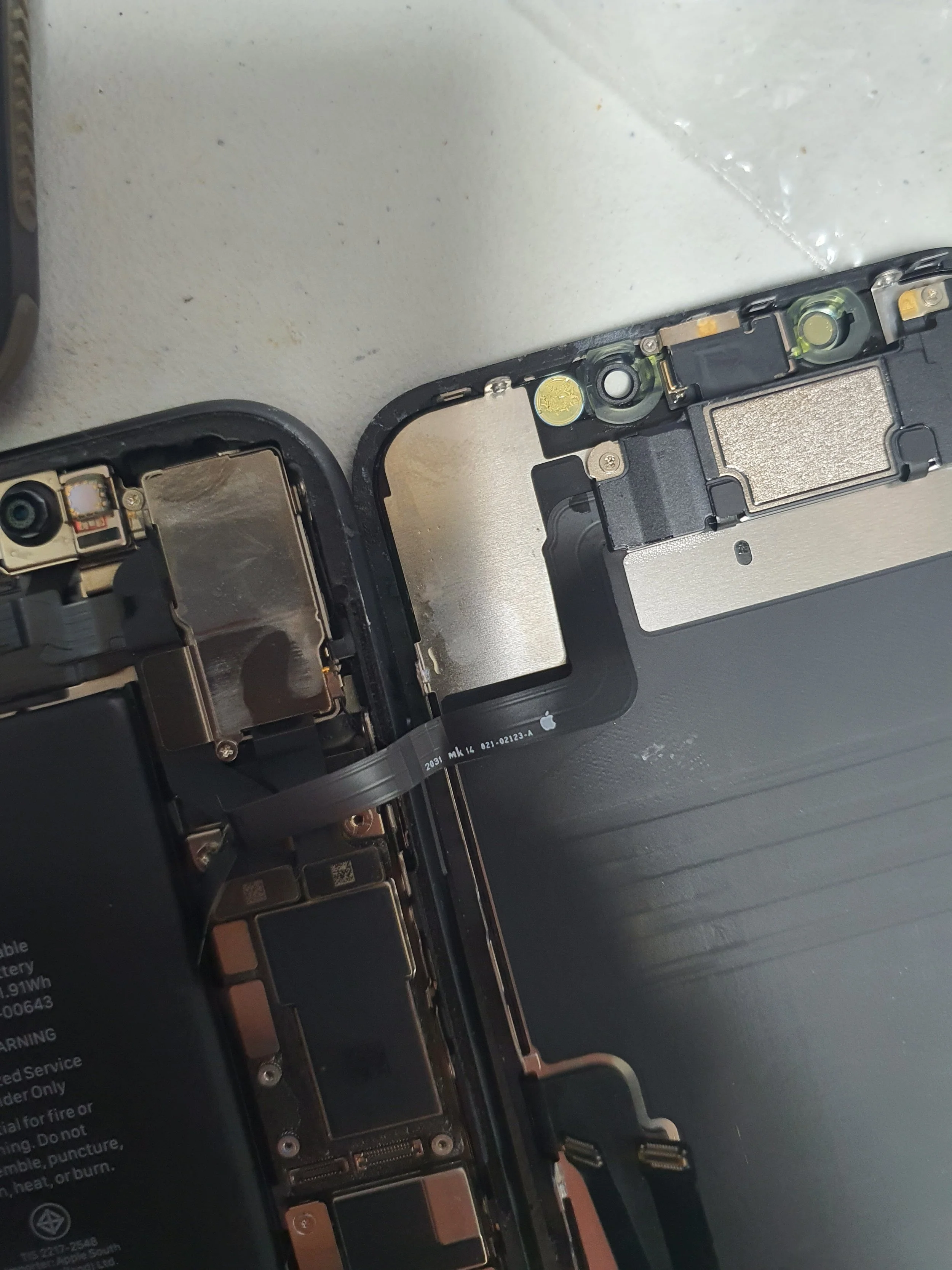 Close-up of a partially disassembled iPhone, showing internal components such as the battery, logic board, and connectors.