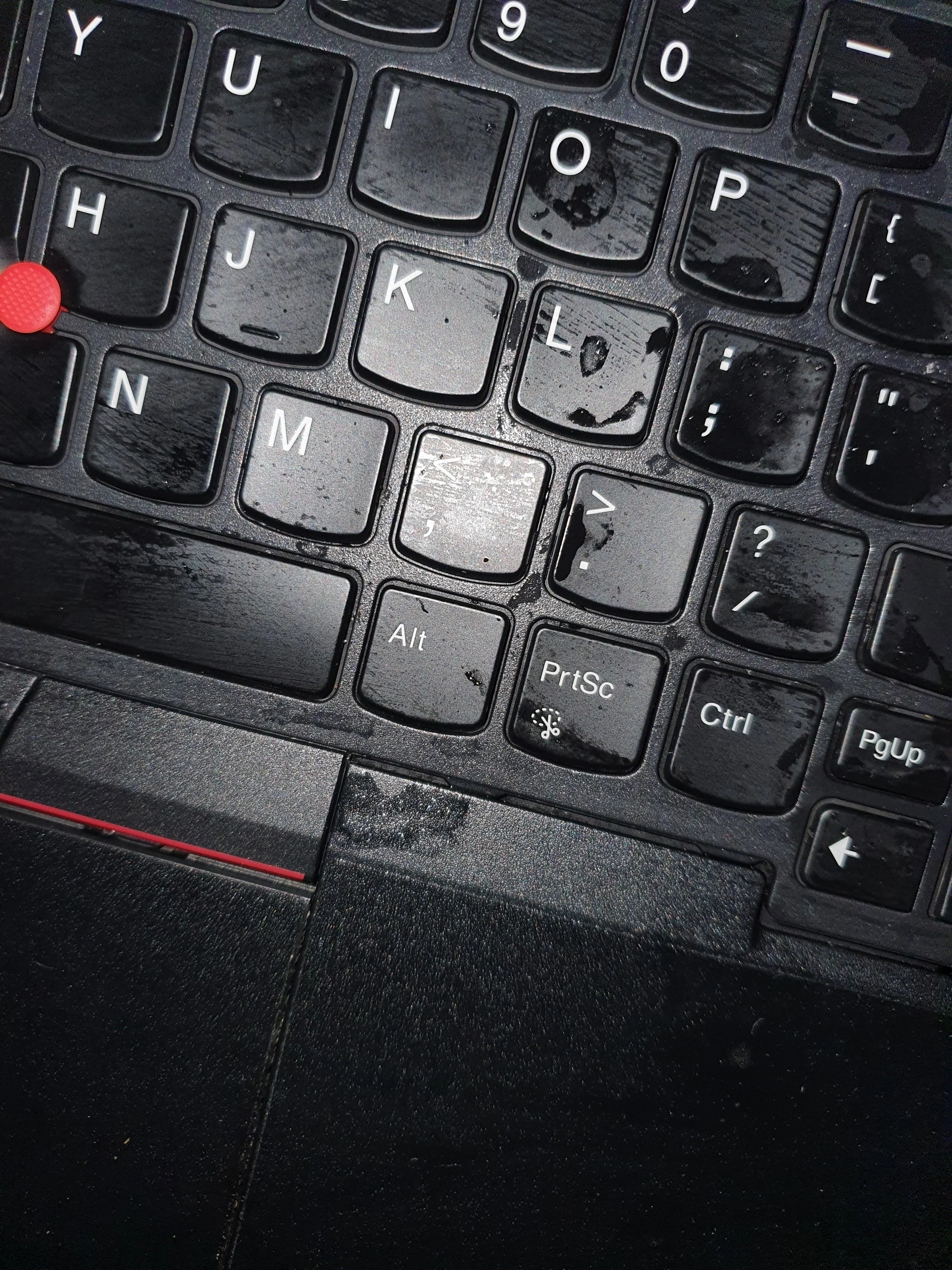 Close-up of a black computer keyboard with visible water spots and dust, showing keys including 'Y', 'U', 'I', 'O', 'P', 'H', 'J', 'K', 'L', 'N', 'M', 'Alt', 'PrtSc', and 'Ctrl'.