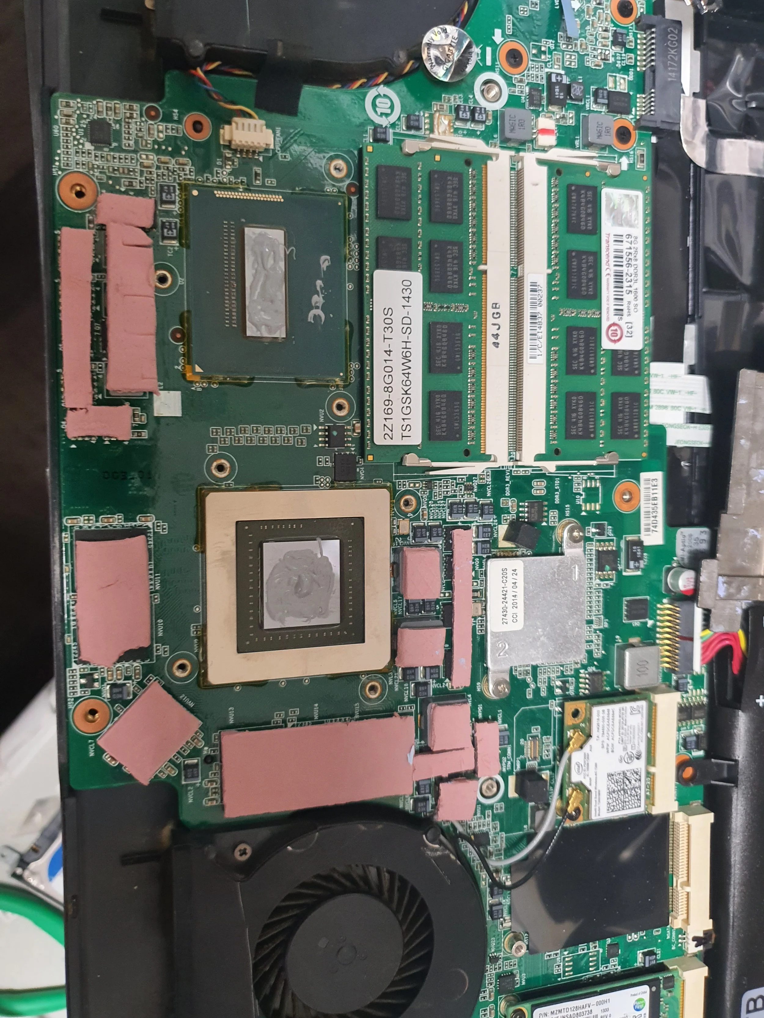 Inside of a laptop showing various electronic components, including a CPU, RAM modules, cooling fan, and other circuit elements.