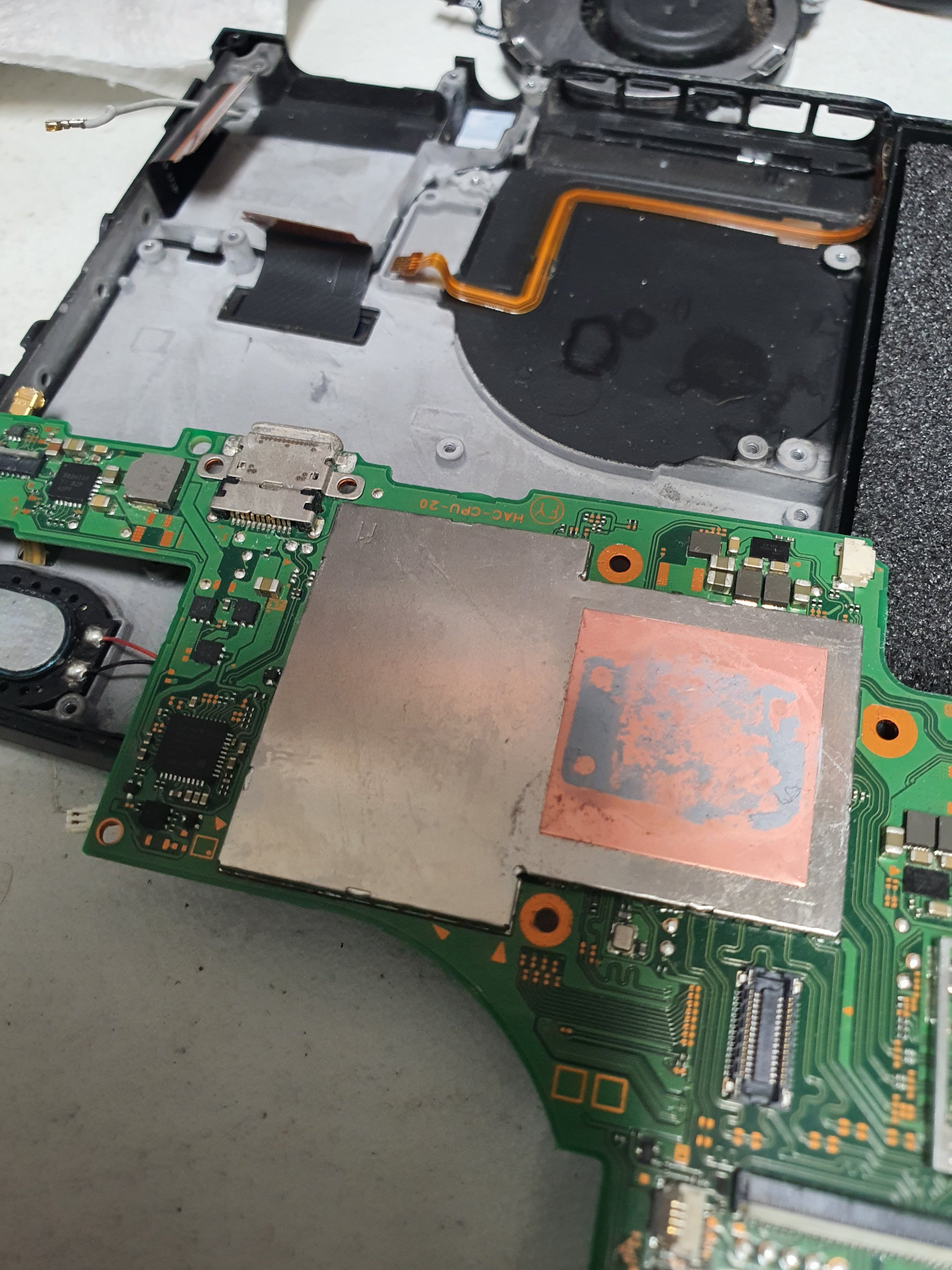 Interior of a disassembled electronic device, likely a laptop or tablet, showing the circuit board, cooling system, and internal components.