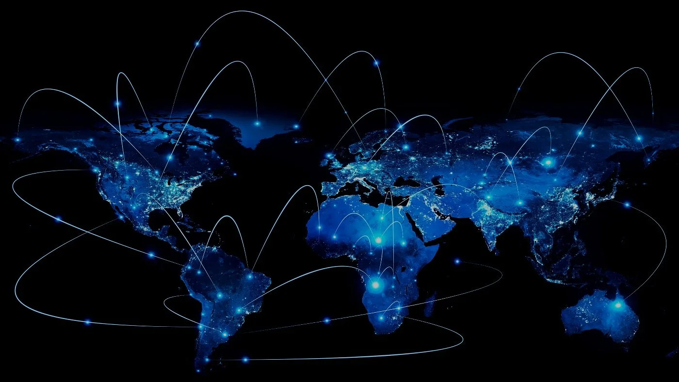 Dark world map with glowing blue lights in major cities and white lines connecting different parts of the world, representing global connectivity.