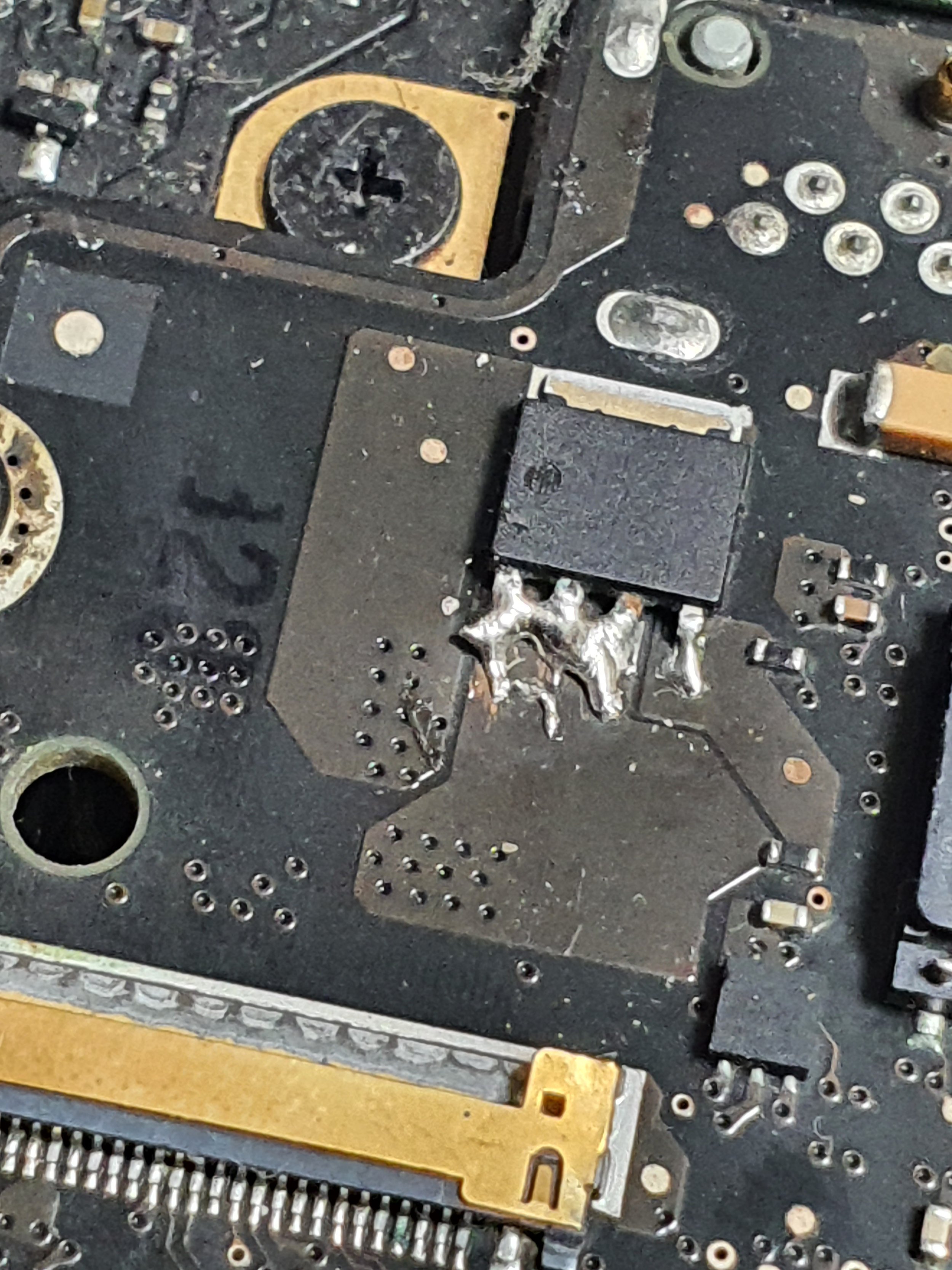 Close-up of a damaged or burned circuit board with solder and electronic components.
