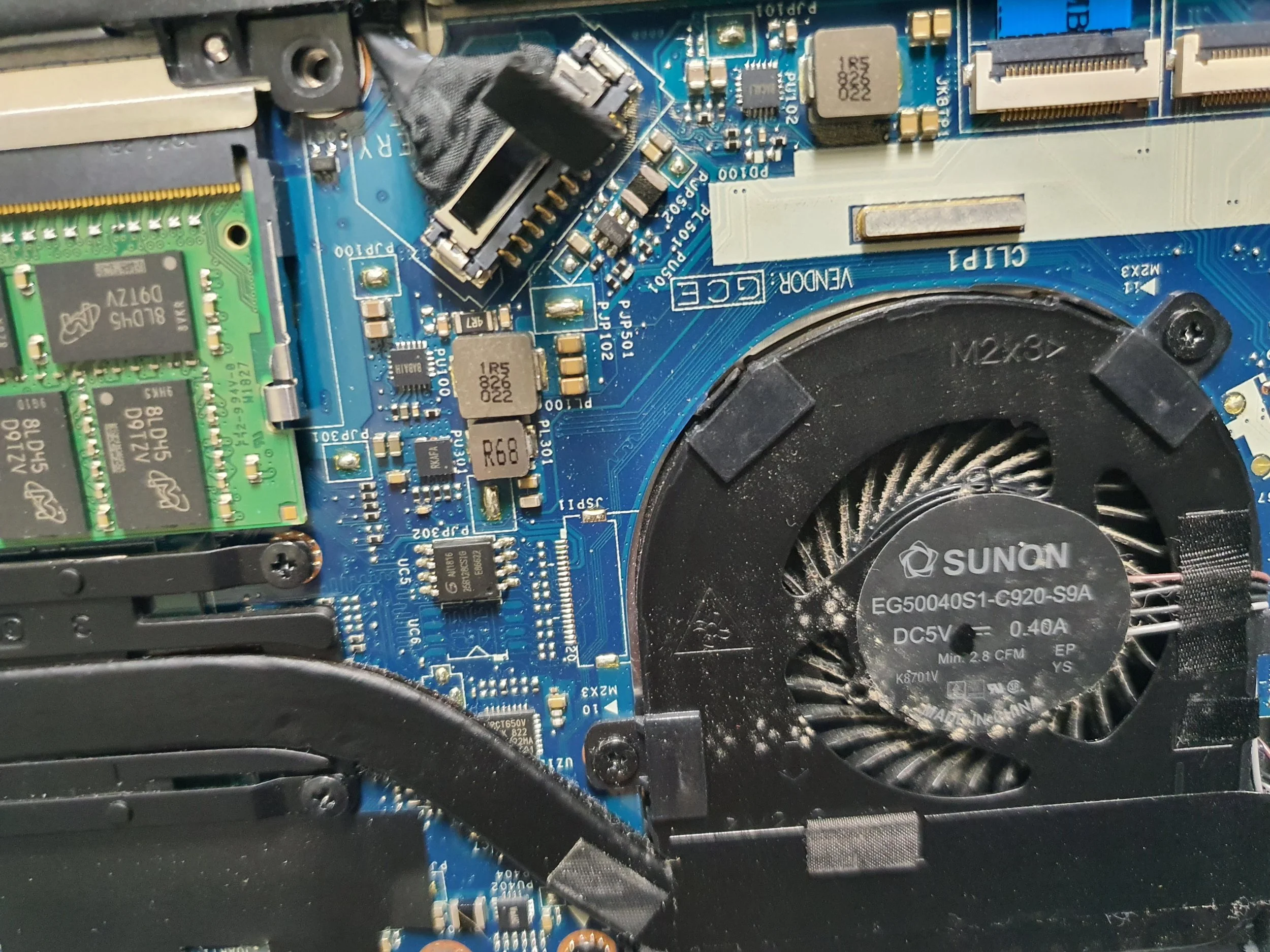 Close-up view of a computer motherboard showing various components, a cooling fan labeled Sunon, and a green RAM module.