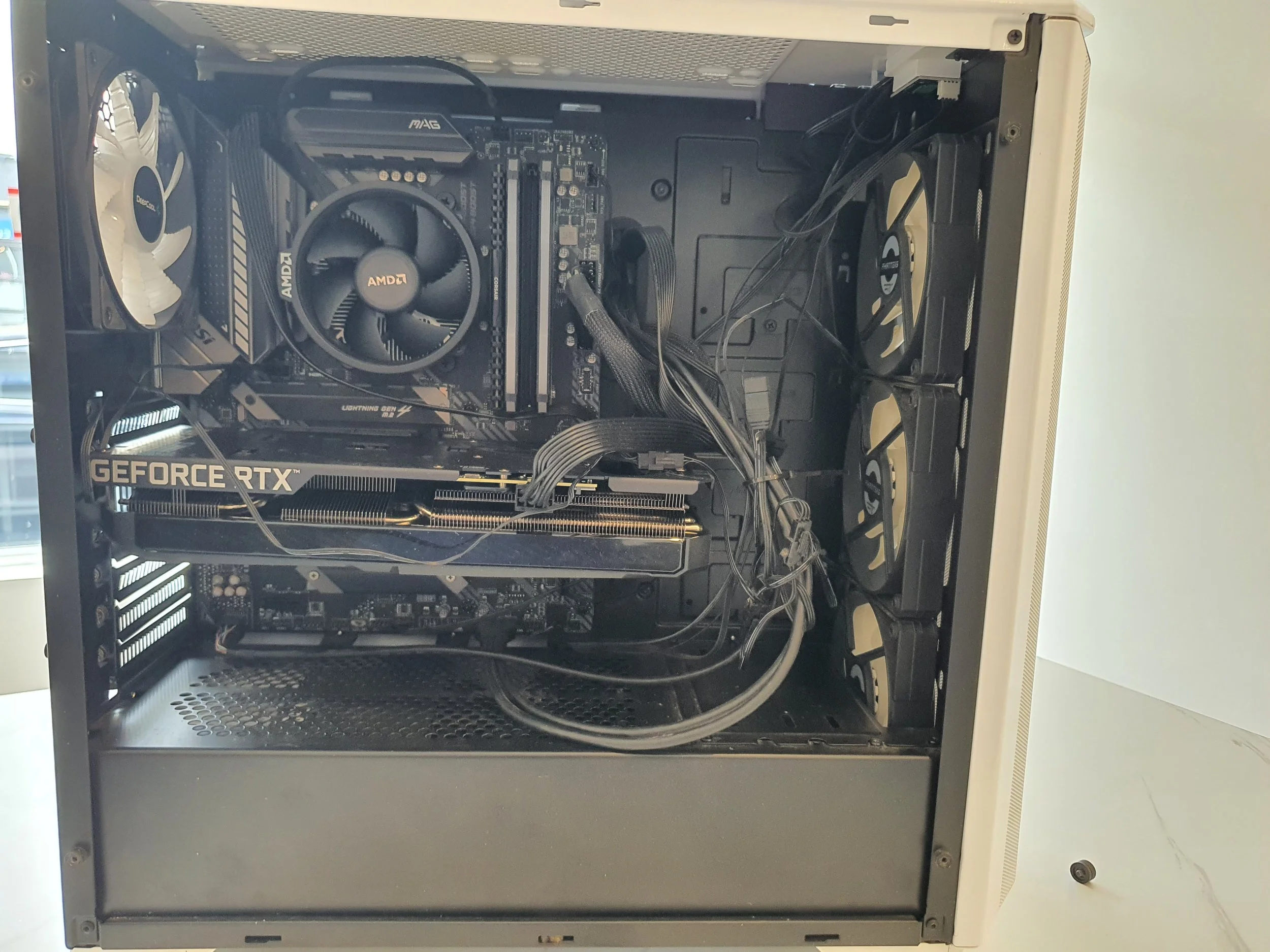 Interior of a desktop computer showing components including a graphics card, motherboard, cooling fans, and power supply unit.