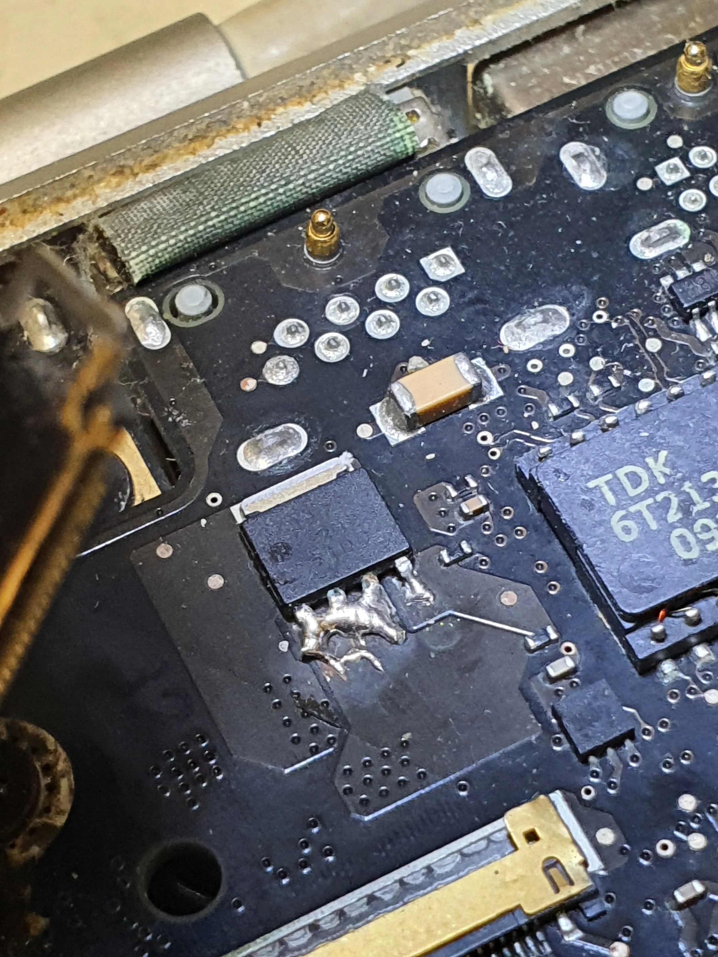 Close-up of a malfunctioning circuit board with burnt solder joints, indicating potential damage from overheating or electrical failure.