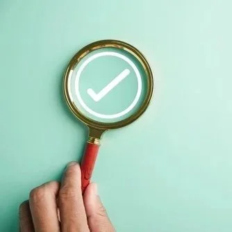 hand holding magnifying glass showing a large tick for checked