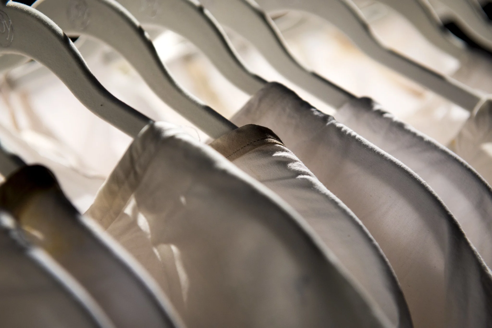 White hospital gowns with some brown staining hanging on white hangers