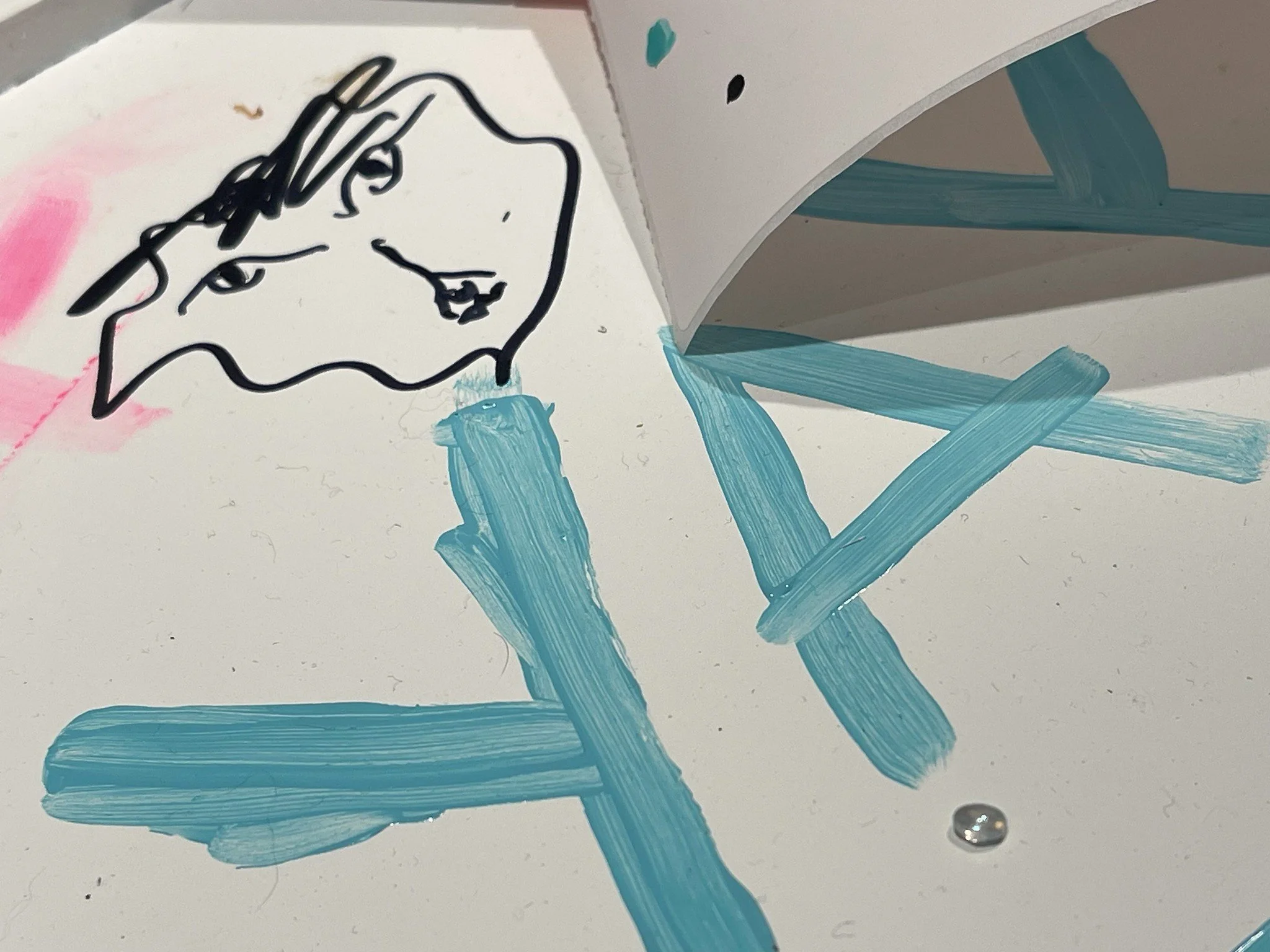 A documentation photo from Amanda Rose's Waystation Generation piece featuring a white surface with the word "Yay" painted on and a sharpie drawing of a face
