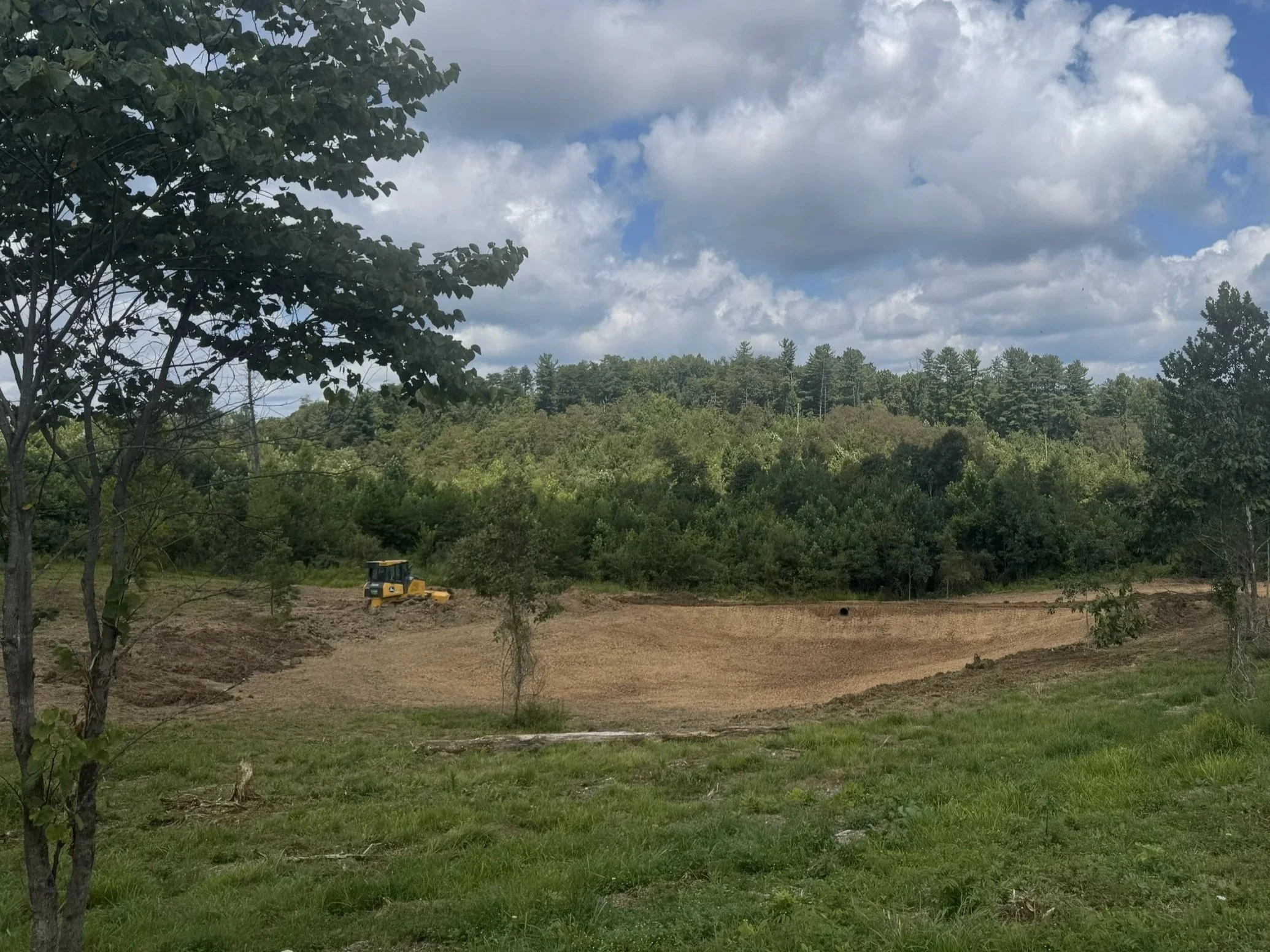 Freshly constructed pond basin with embankment and construction equipment, illustrating Eden Hills Land Management’s pond construction and site-preparation services.