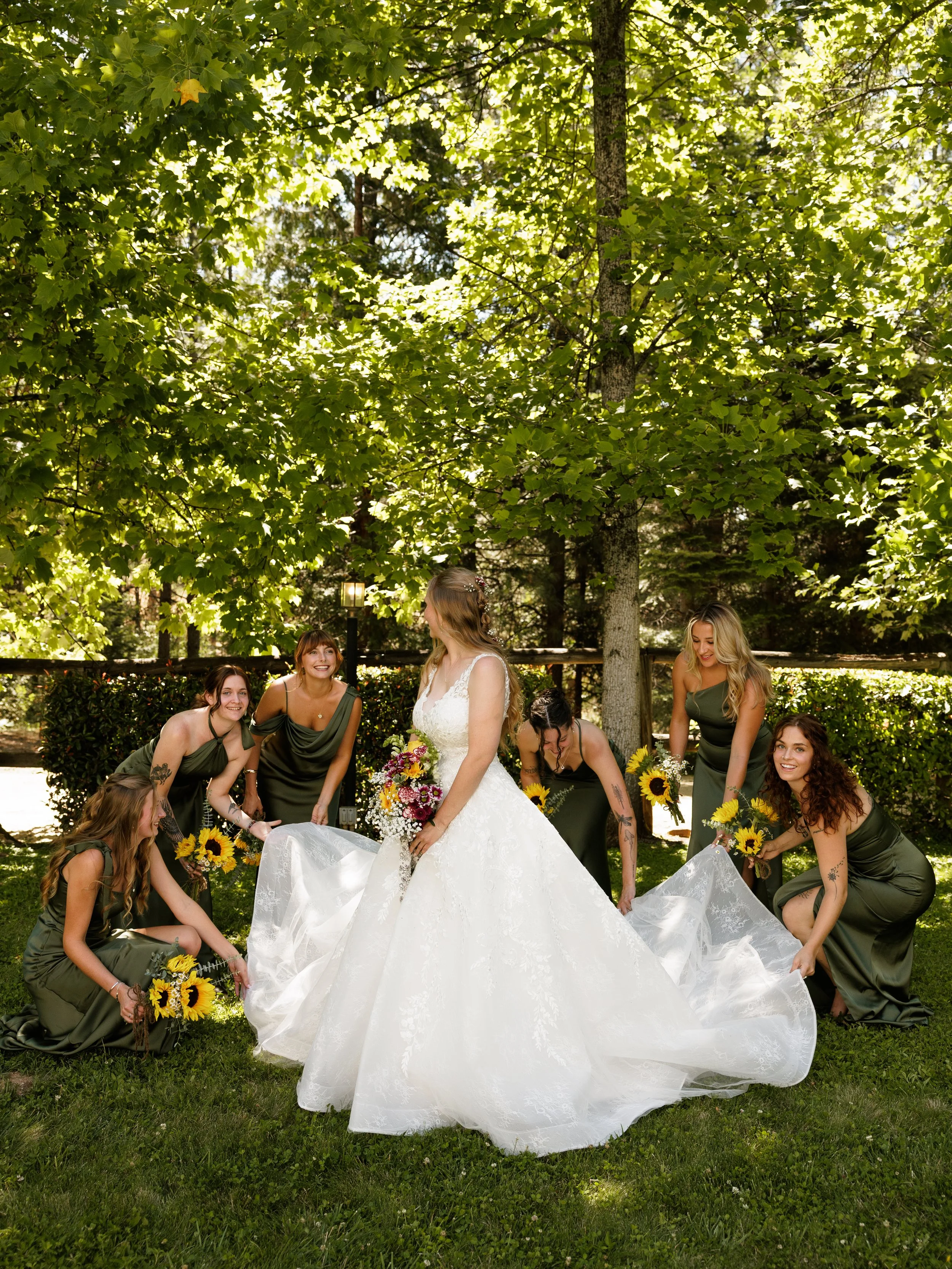 Bride surrounded by smiling bridesmaids fixing her dress
