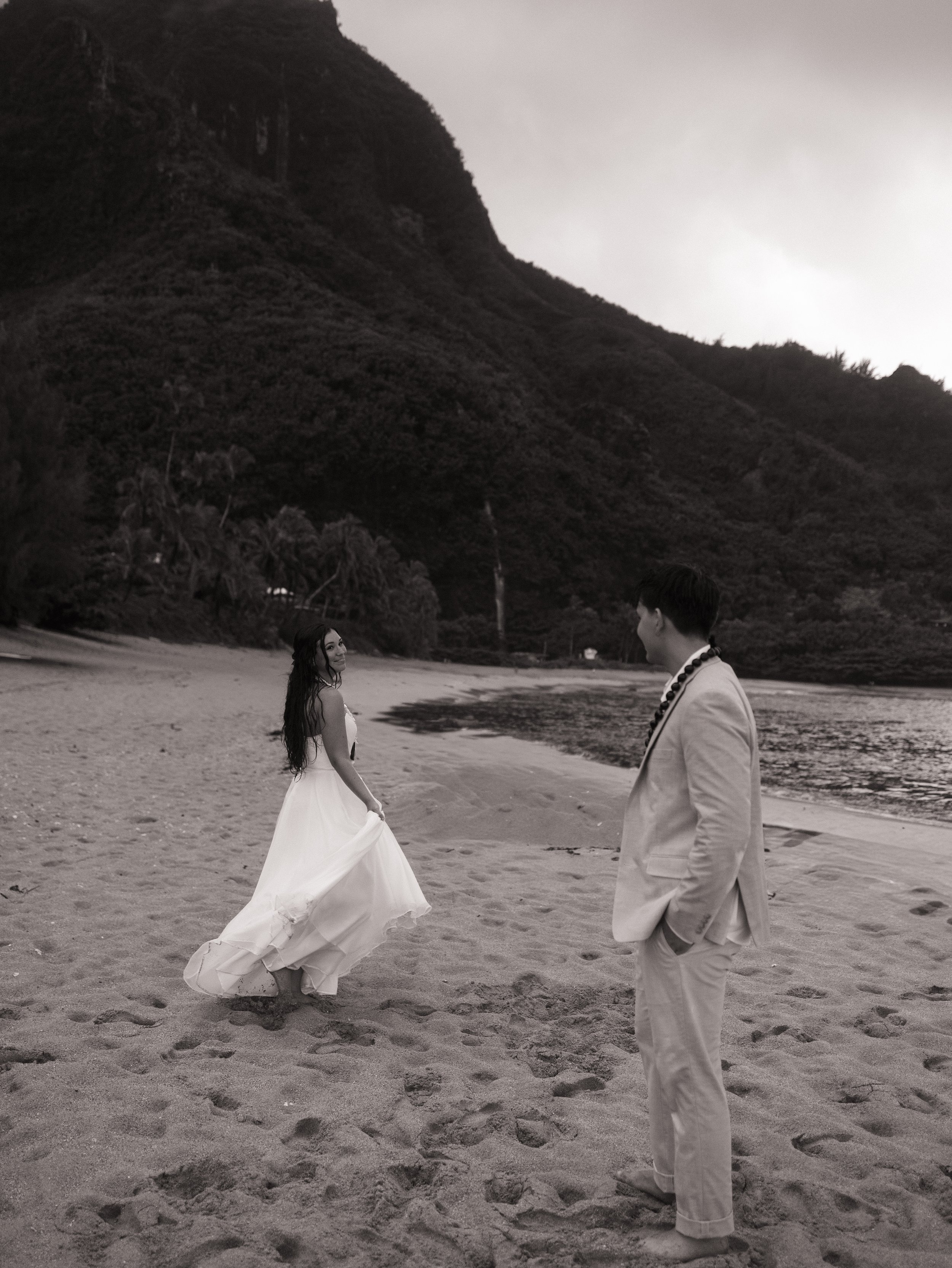 Outdoor wedding reception with bridesmaids and guests near a sign that reads "Jonah & Natalie" with scenic mountains and trees in the background.