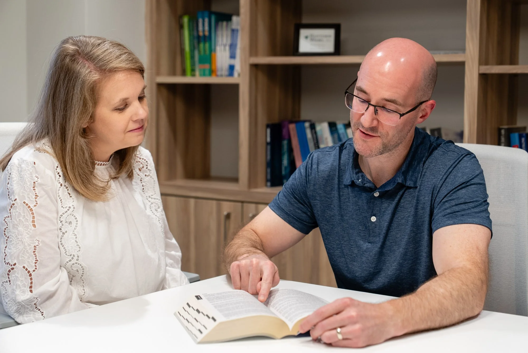 Two colleagues discussing a book in an office.
