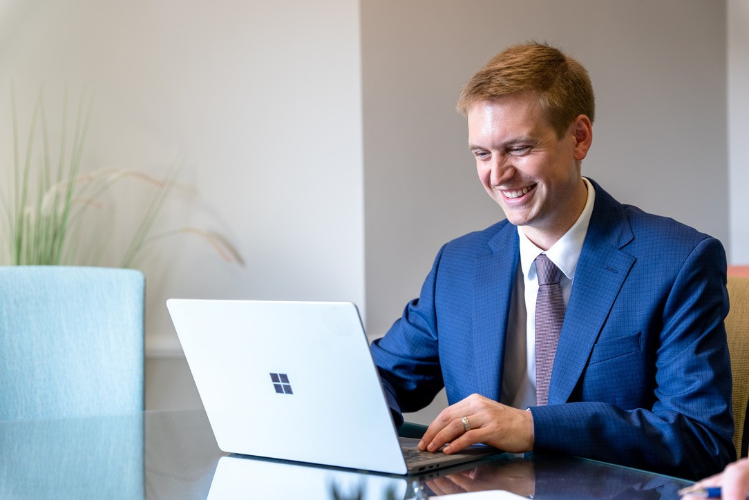 Tax professionals near me: a smiling certified public accountant in a modern office, using a laptop at a glass desk, with clear lighting and organized workspace.