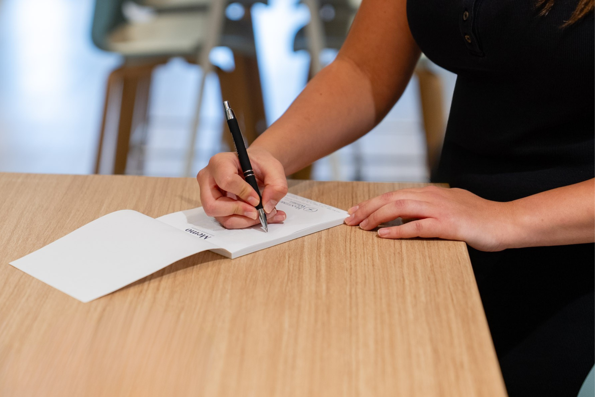 Close-up of a person in a black top signing tax preparation documents