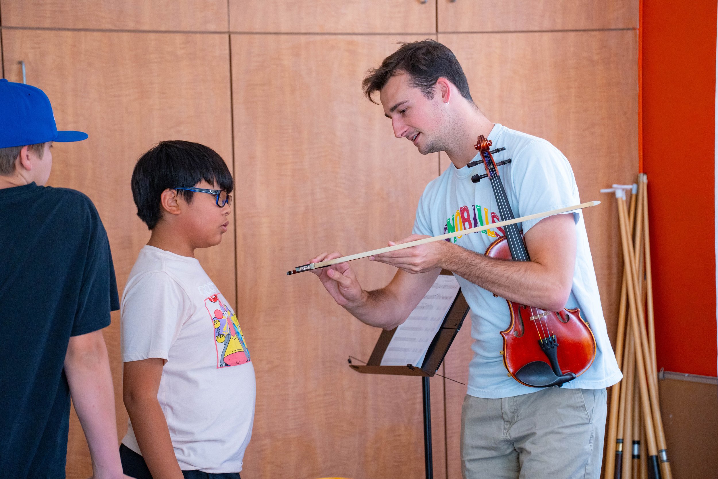 Peter helps a violin student refine his bow hold so that he can play with a deeper sound.