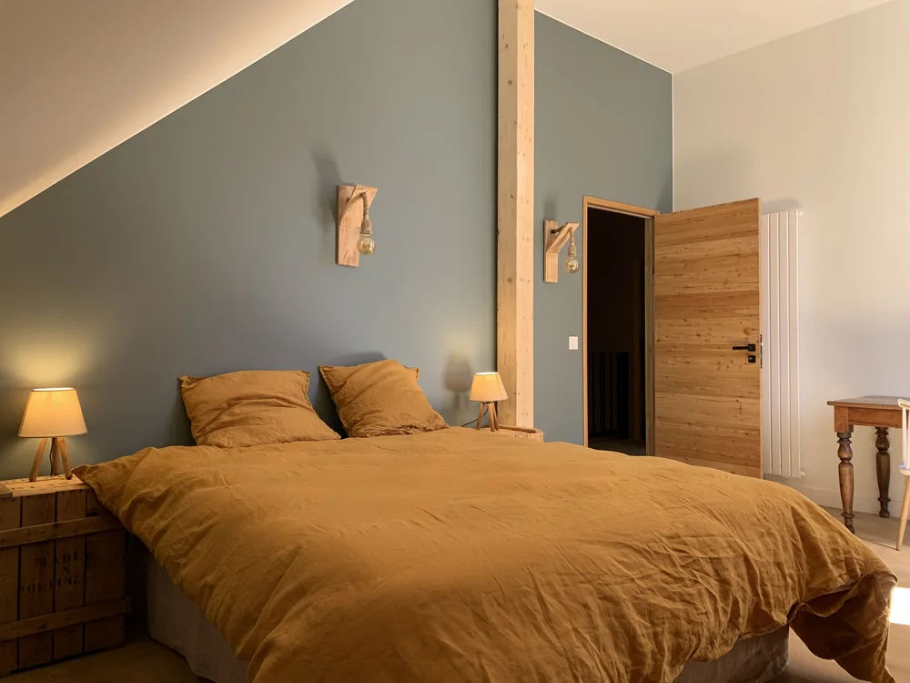 Chambre aux murs vert pastel avec lit double et housse en lin lavé