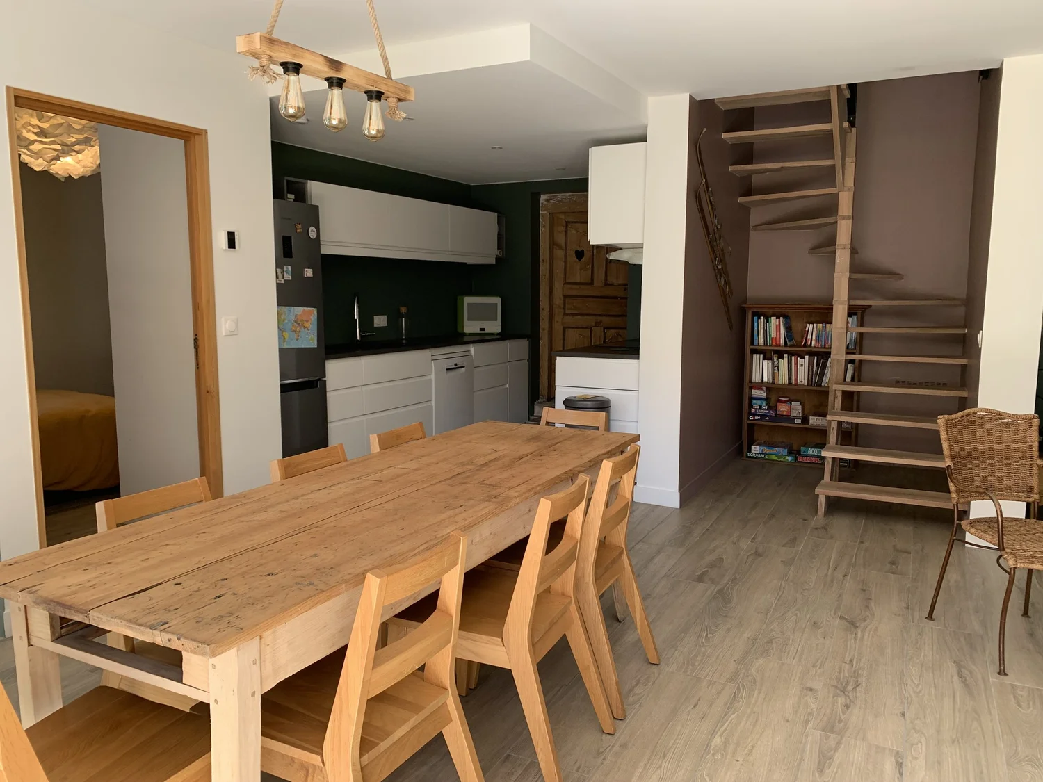 Cuisine et salle à manger avec table en bois, huit chaises, escalier en bois