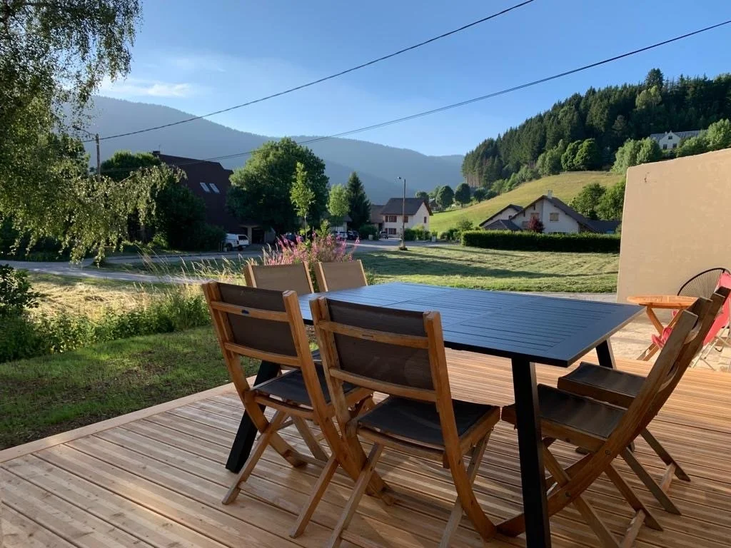 Grande table sur la terrasse en bois, face au village de Méaudre