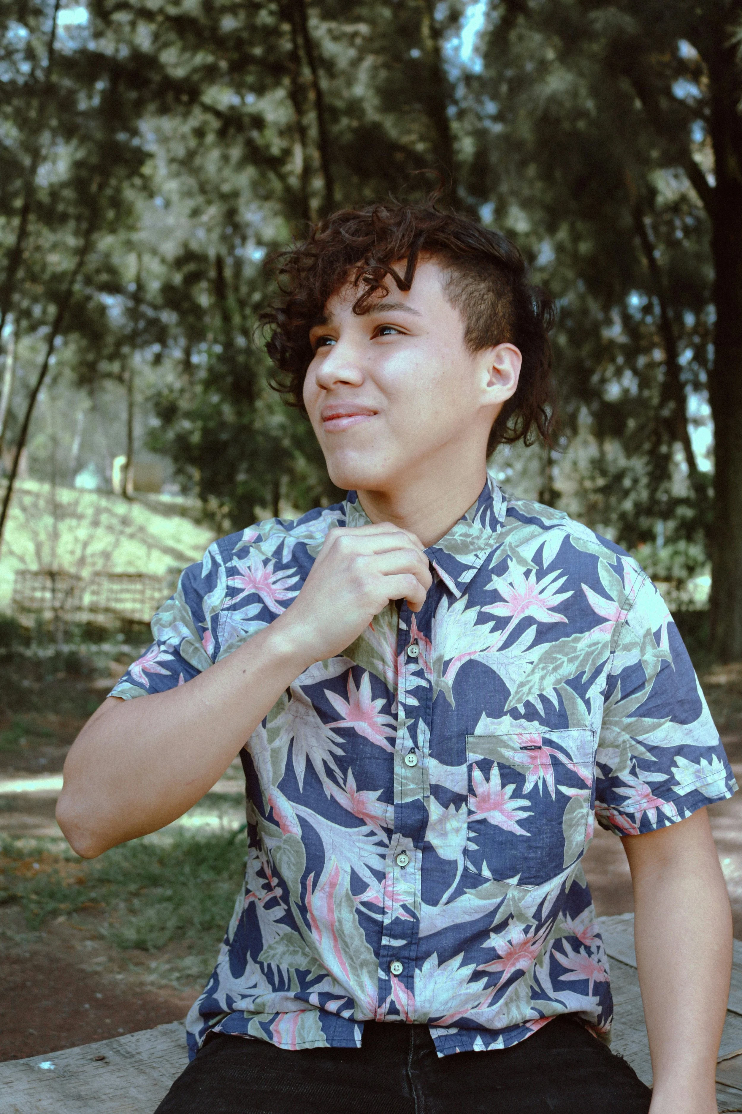 person with short curly hair wearing Hawaiian shirt smiling