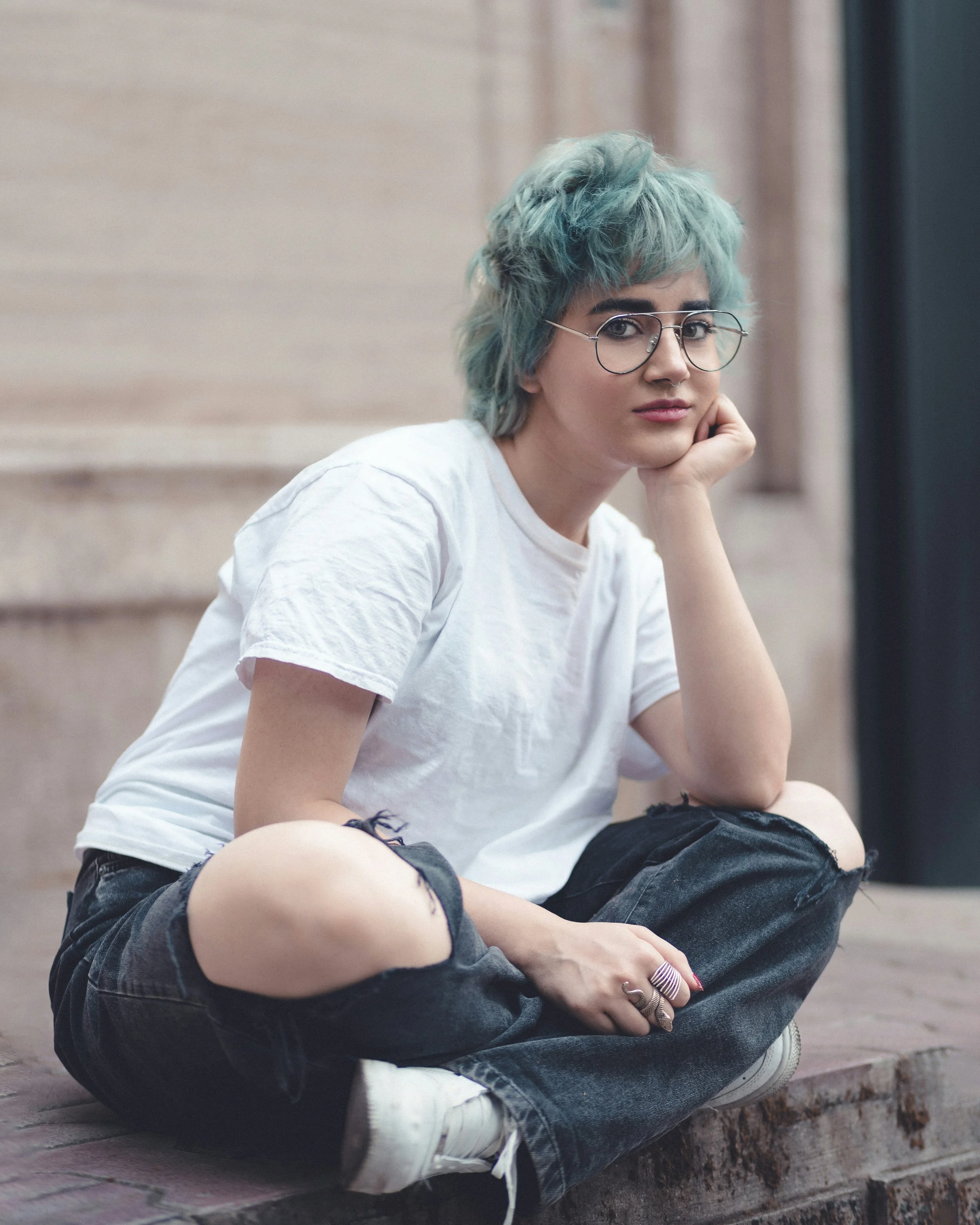 young woman with green hair and glasses sitting