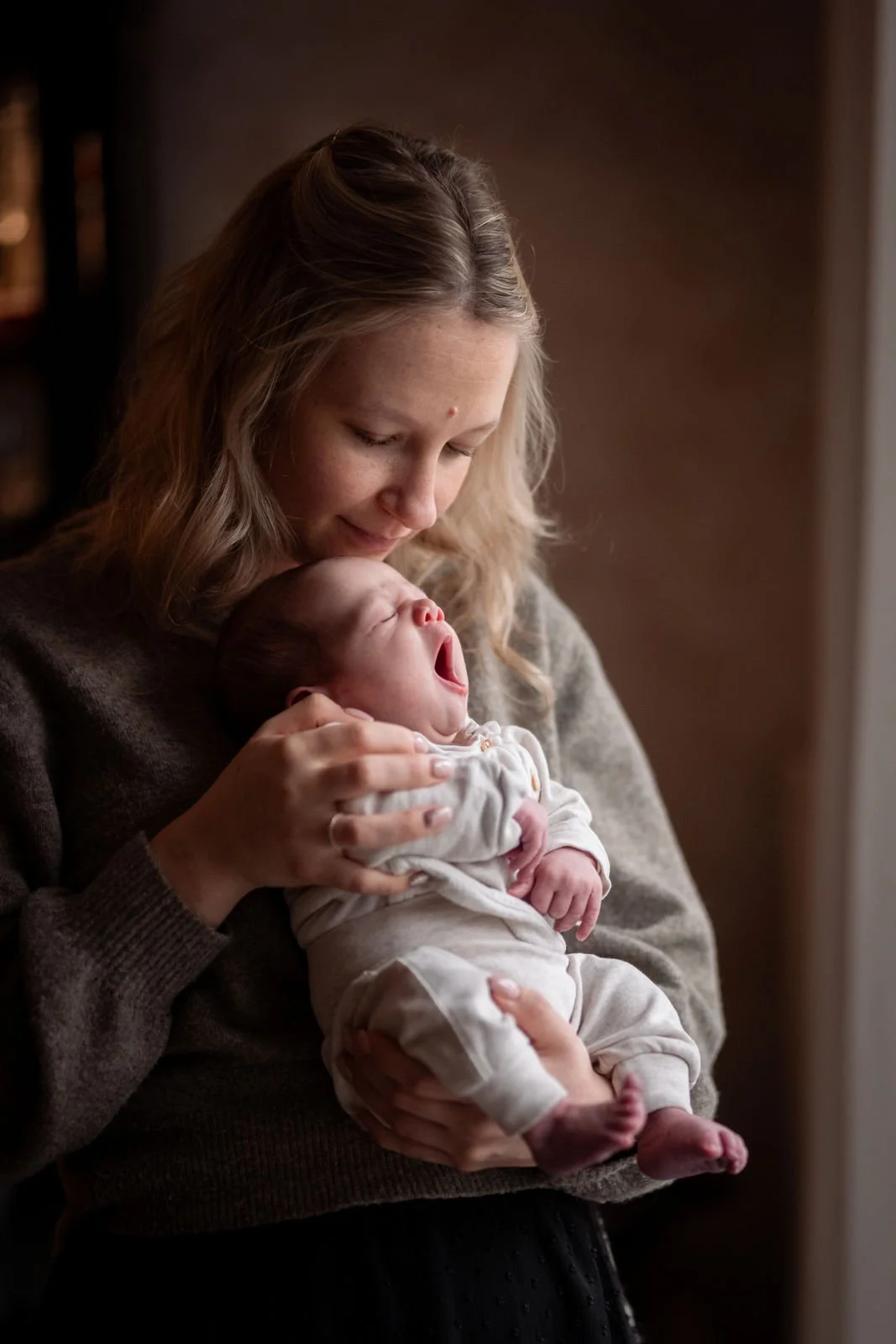 Eine Frau hält ein schlafendes Baby in den Armen, die Szene ist warm und gemütlich.