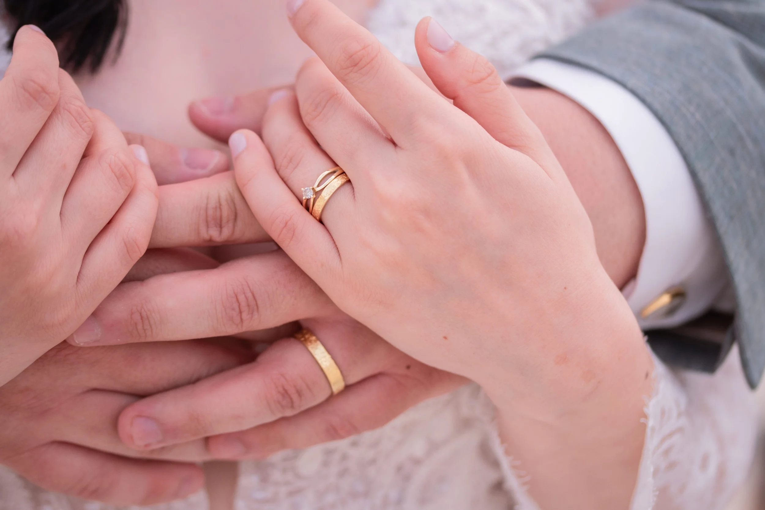 Nahaufnahme von mehreren Händen, die sich auf eine Hochzeit oder Verlobung vorzubereiten, mit Eheringen und Verlobungsring, getragen auf Damen- und Herrenhänden.