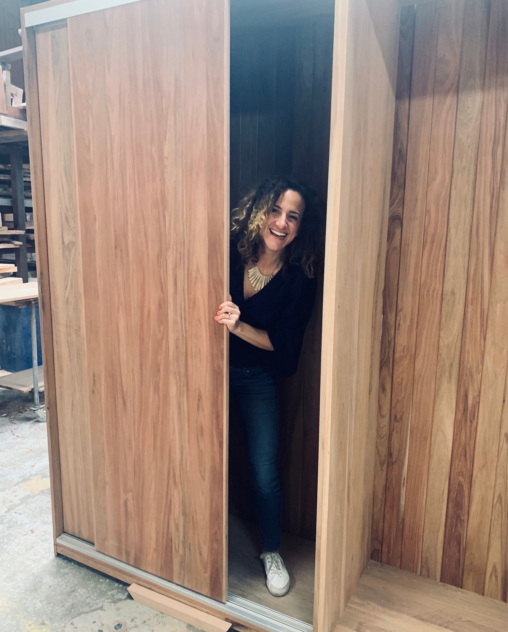 Interior designer and professional home organiser examining a custom wooden wardrobe she designed in a workshop in Sydney.