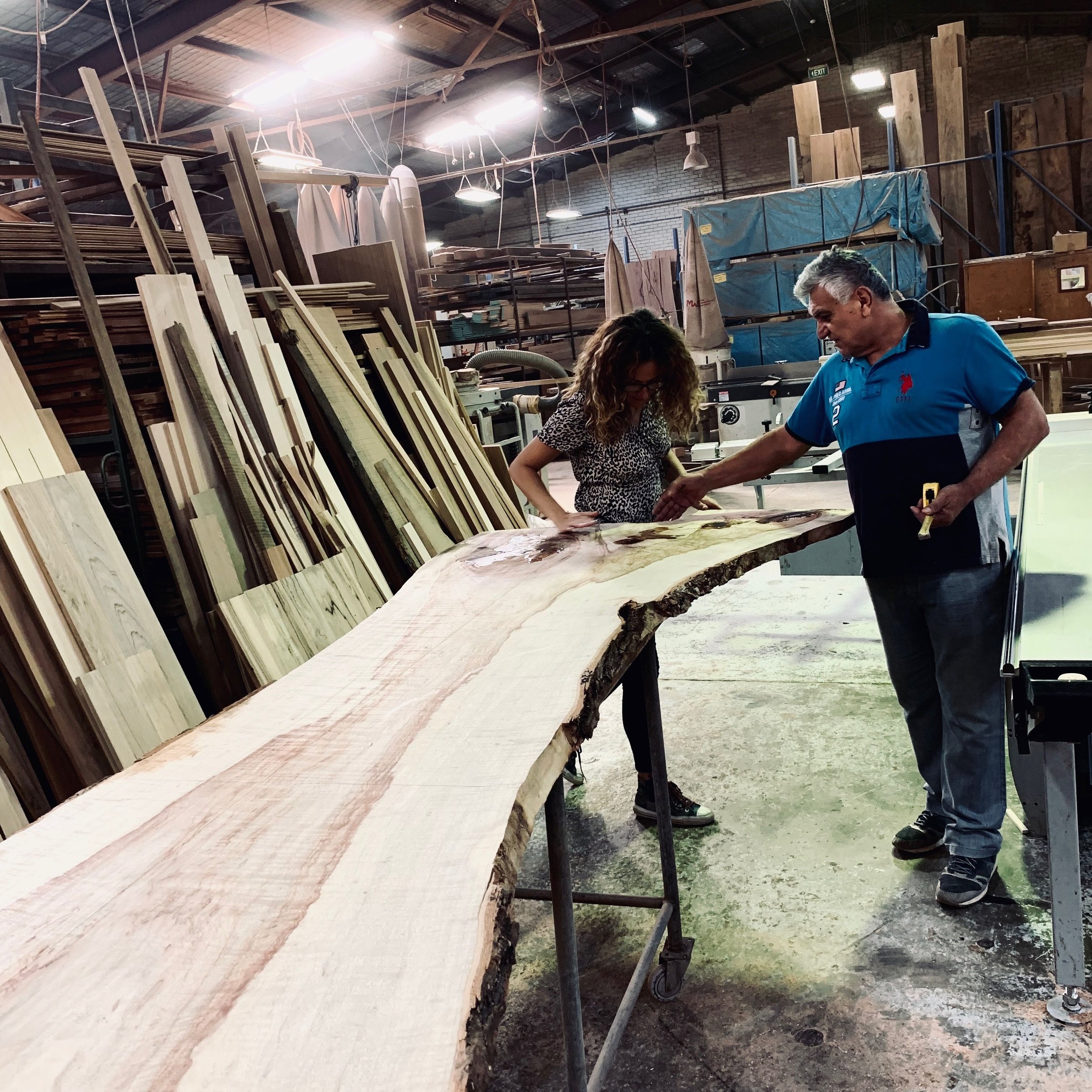 Professional home organiser working on custom slab table in workshop.