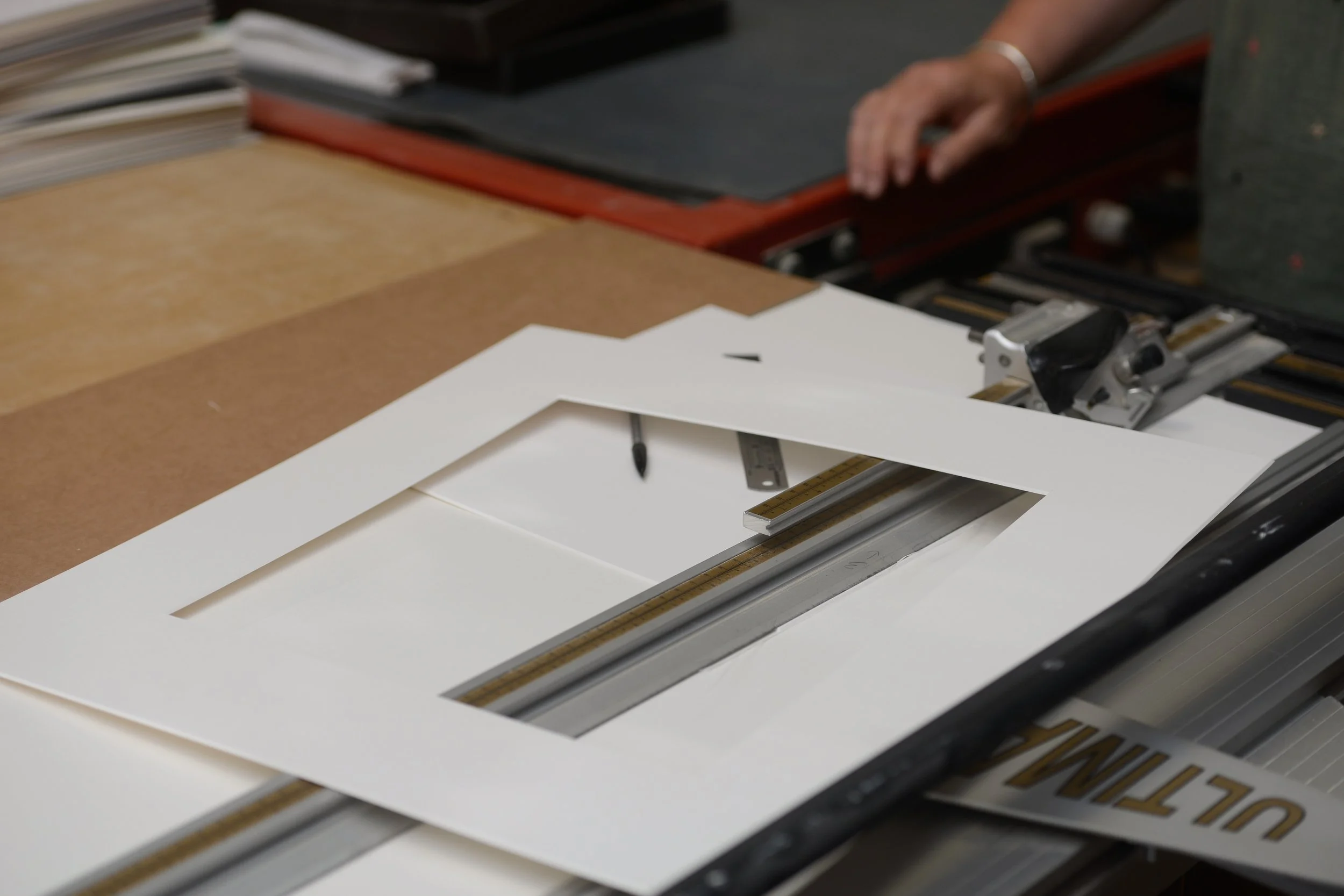 A white paper frame placed on a digital cutting machine with a person’s hand visible in the background.