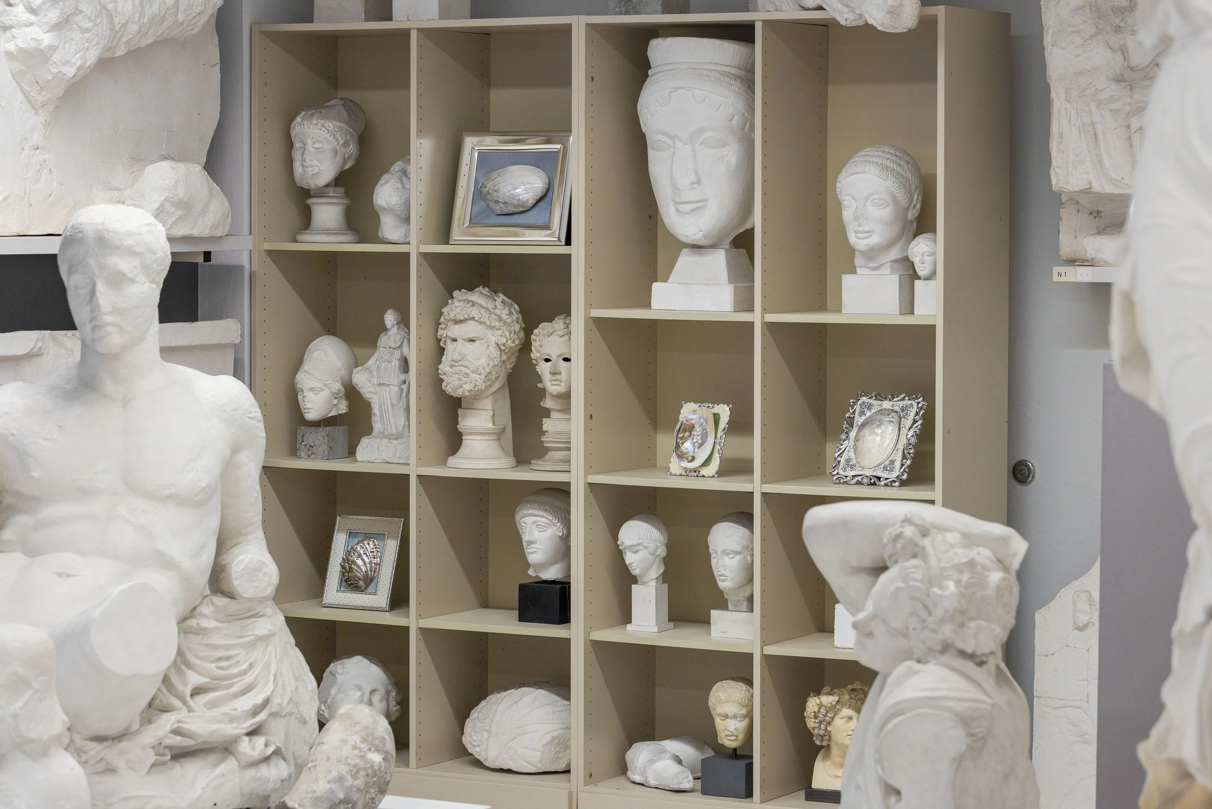 Verschiedene weiße Skulpturen und Büsten aus Marmor auf einem Bücherregal