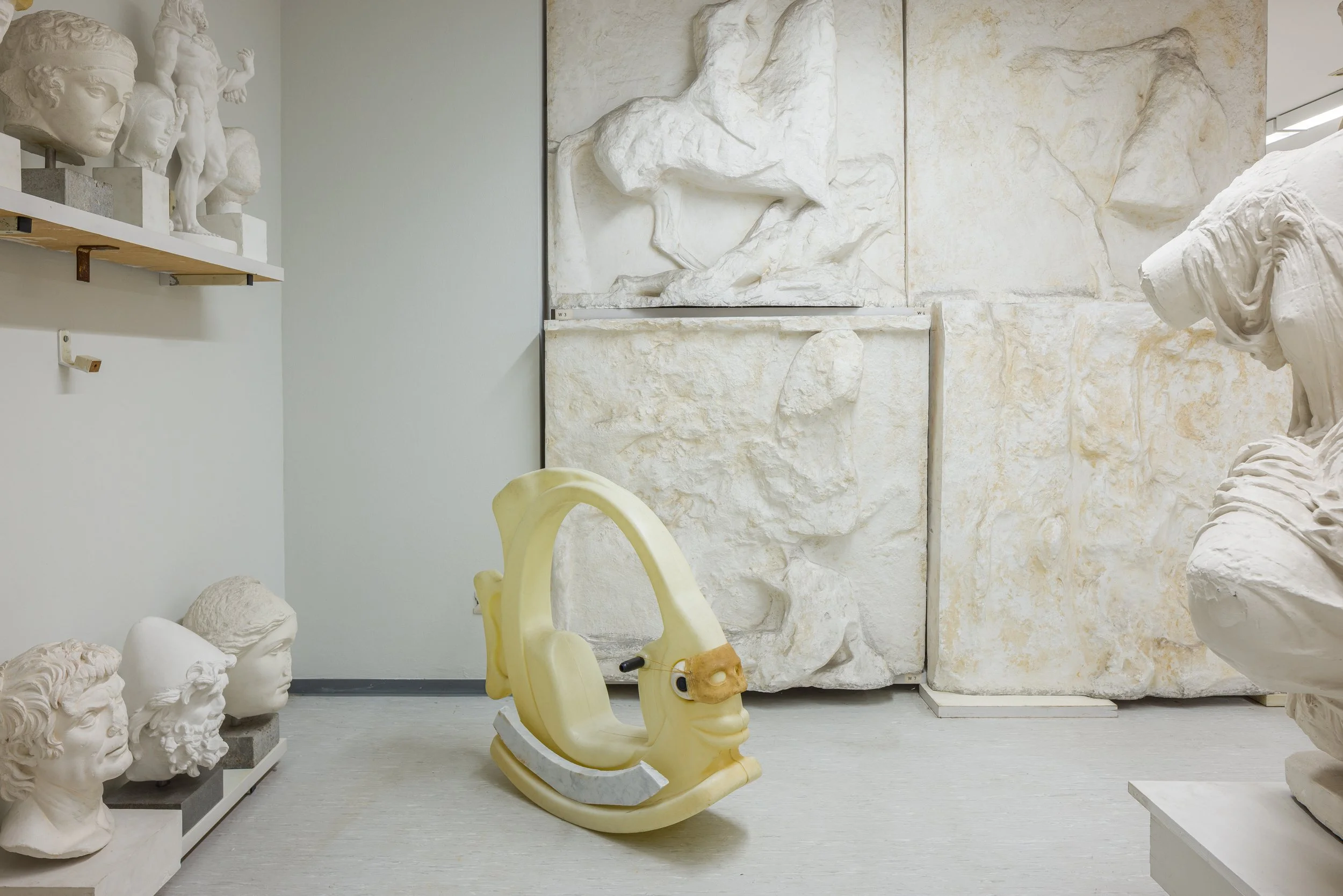 Innenraum eines Museums mit Skulpturen, Antikenköpfen und einer Saugroboter in Form eines Dinosauriers.