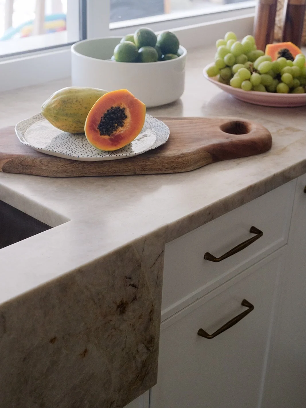 A kitchen should feel collected, not constructed.

Stone with movement.
Brass that warms over time.
Tiles that carry color without overpowering the light.

European restraint meets tropical ease &mdash; where mornings start slowly, fruit sits on the 