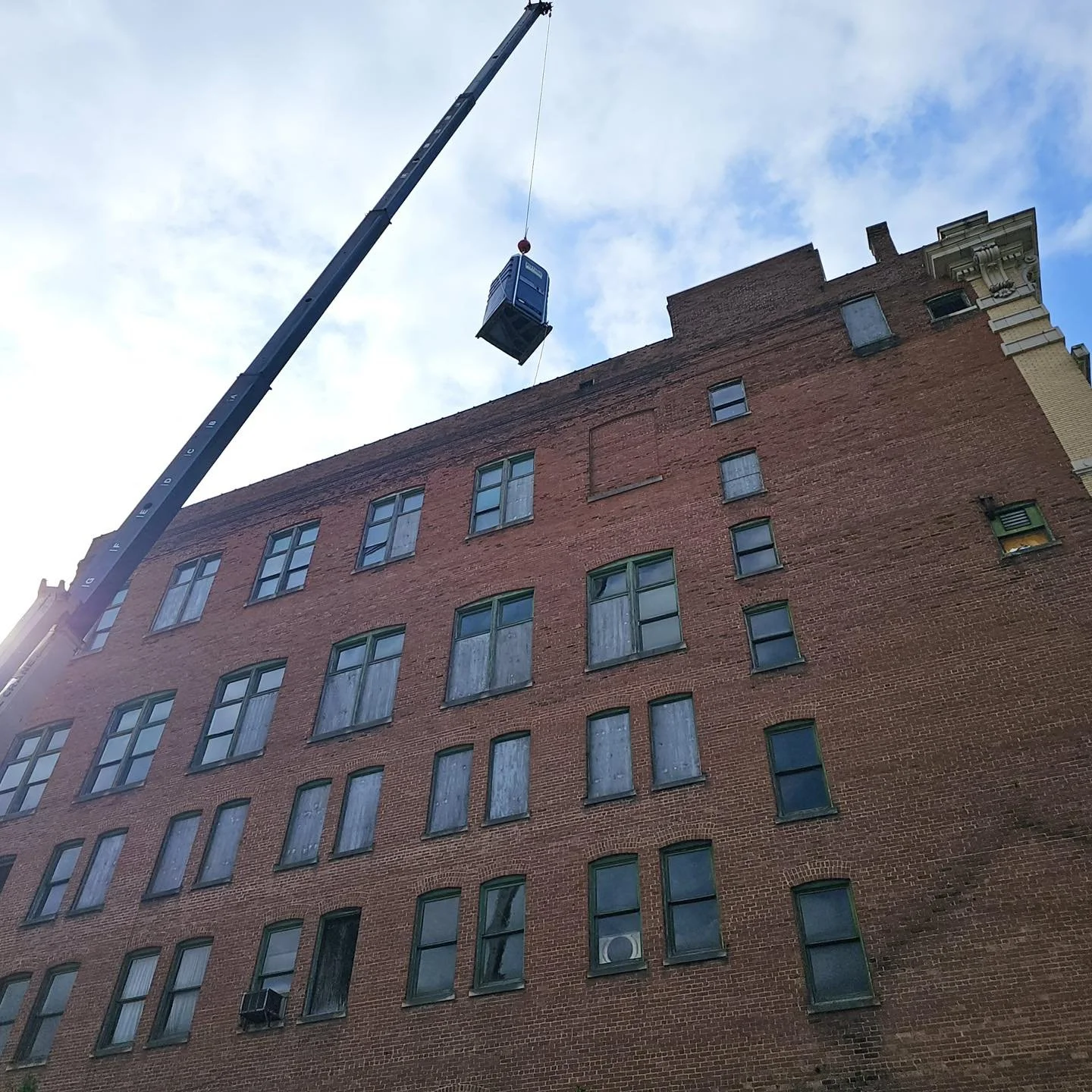 Porta John being placed on top of a high-rise building for roofing construction site.