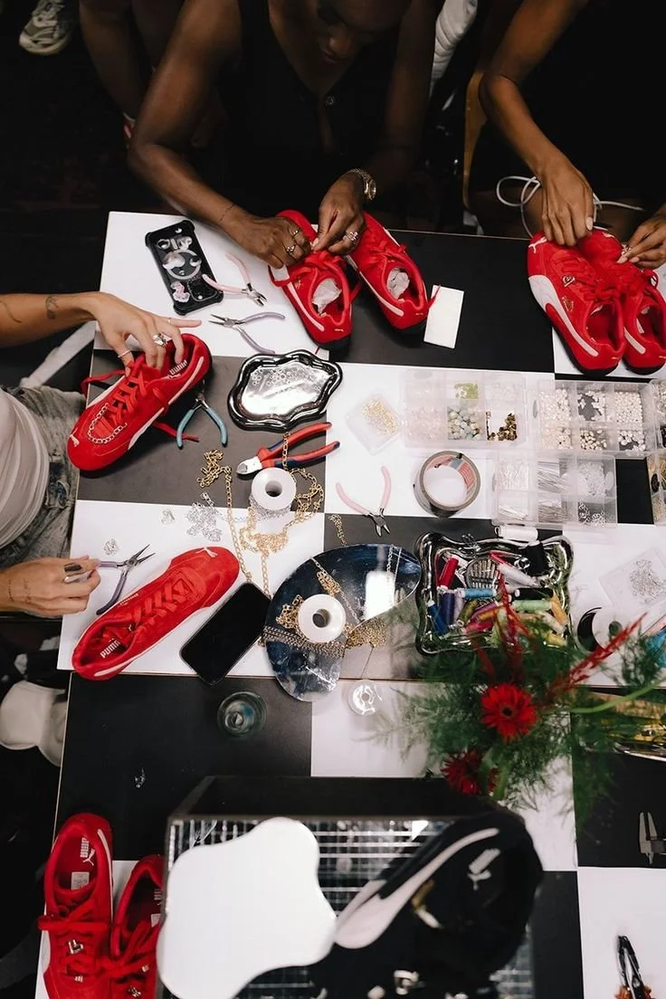 Puma shoe customization bar displaying matching red sneakers with chains, beads, and decorative accessories for personalization, creating an interactive brand activation experience.