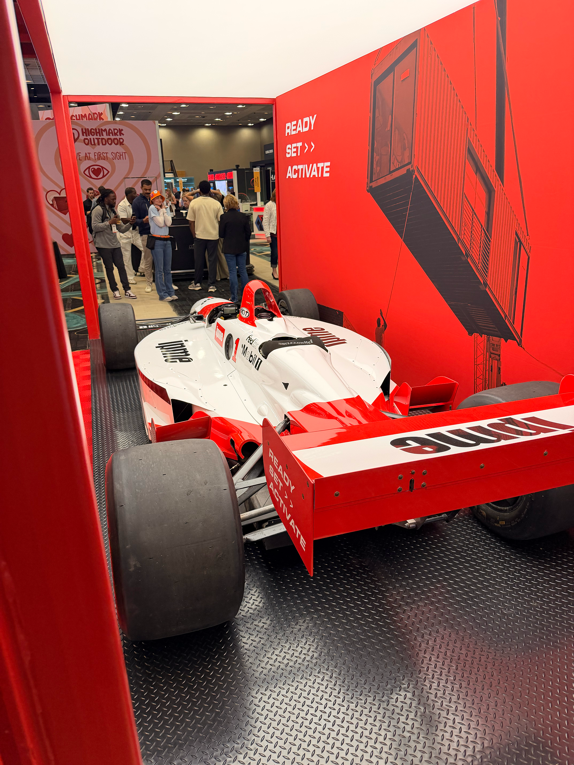 B2B experiential marketing trade show booth activation at Event Marketer Summit EMS 2026 featuring an interactive racing car simulator, immersive curved LED display screen,