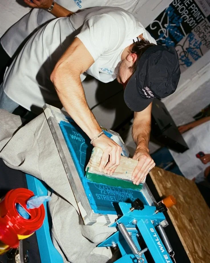 Man screen-printing a custom design on a garment at a live activation event showcasing personalization
