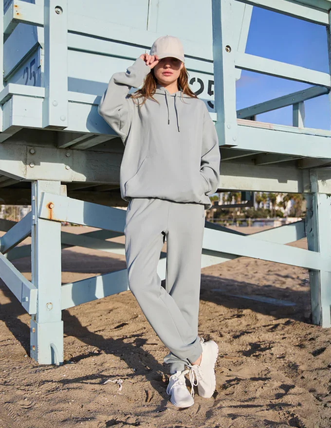 Model sporting a sweatsuit set in sage by CoffeeThread™ by Elemental, showcasing sustainable fashion.