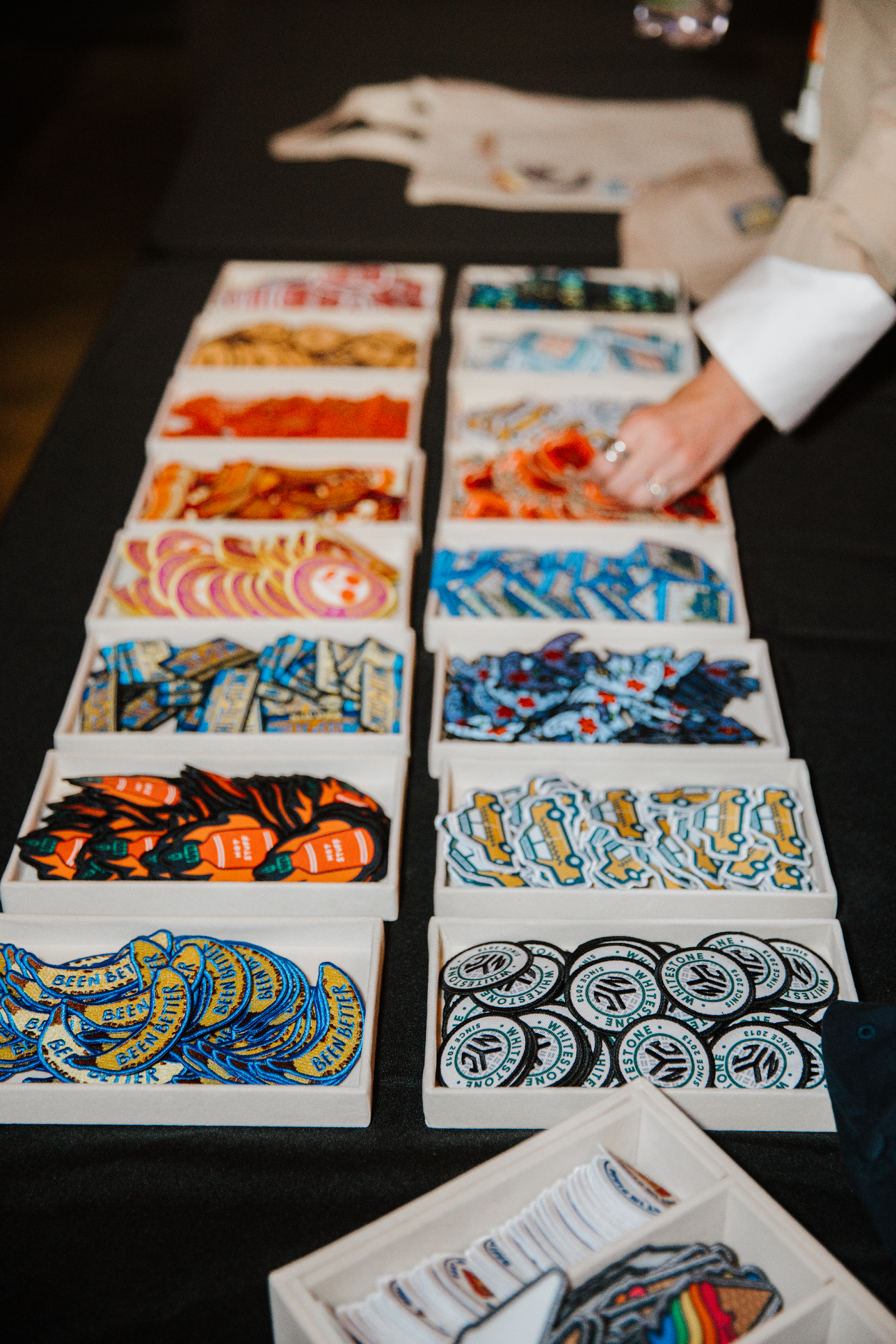 A hand selecting colorful patches from containers to create a custom, one-of-a-kind piece.