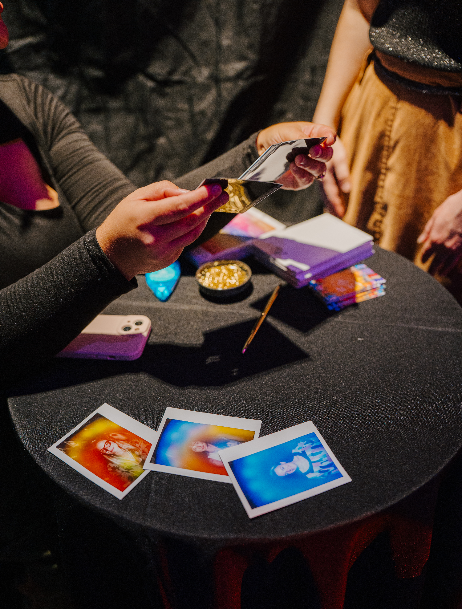Array of aura photographs displayed on a table, with a hand holding 2 to showcase the differences in each while encouraging conversation and meaning.