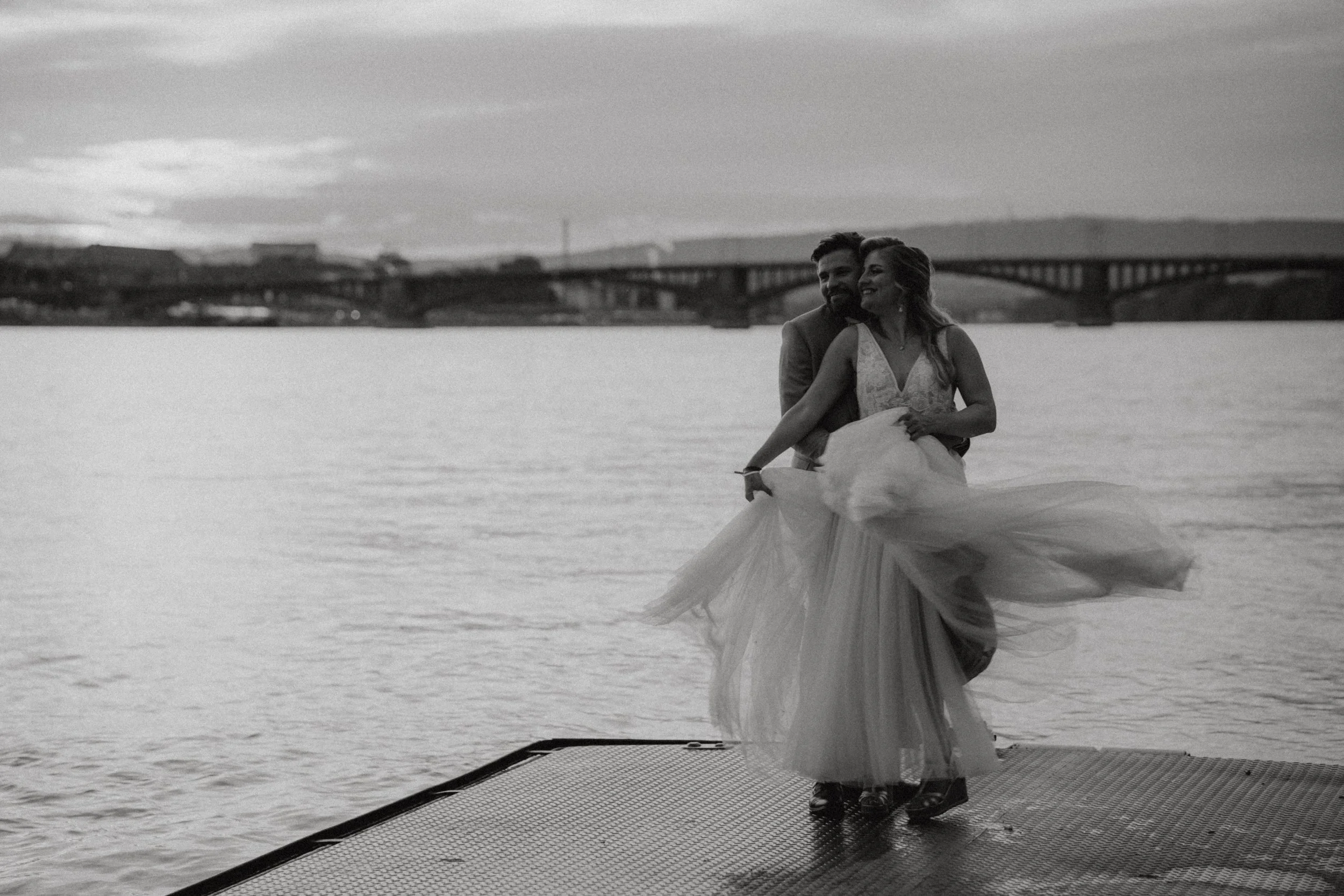 Hochzeitspaar auf einem Steg am Wasser