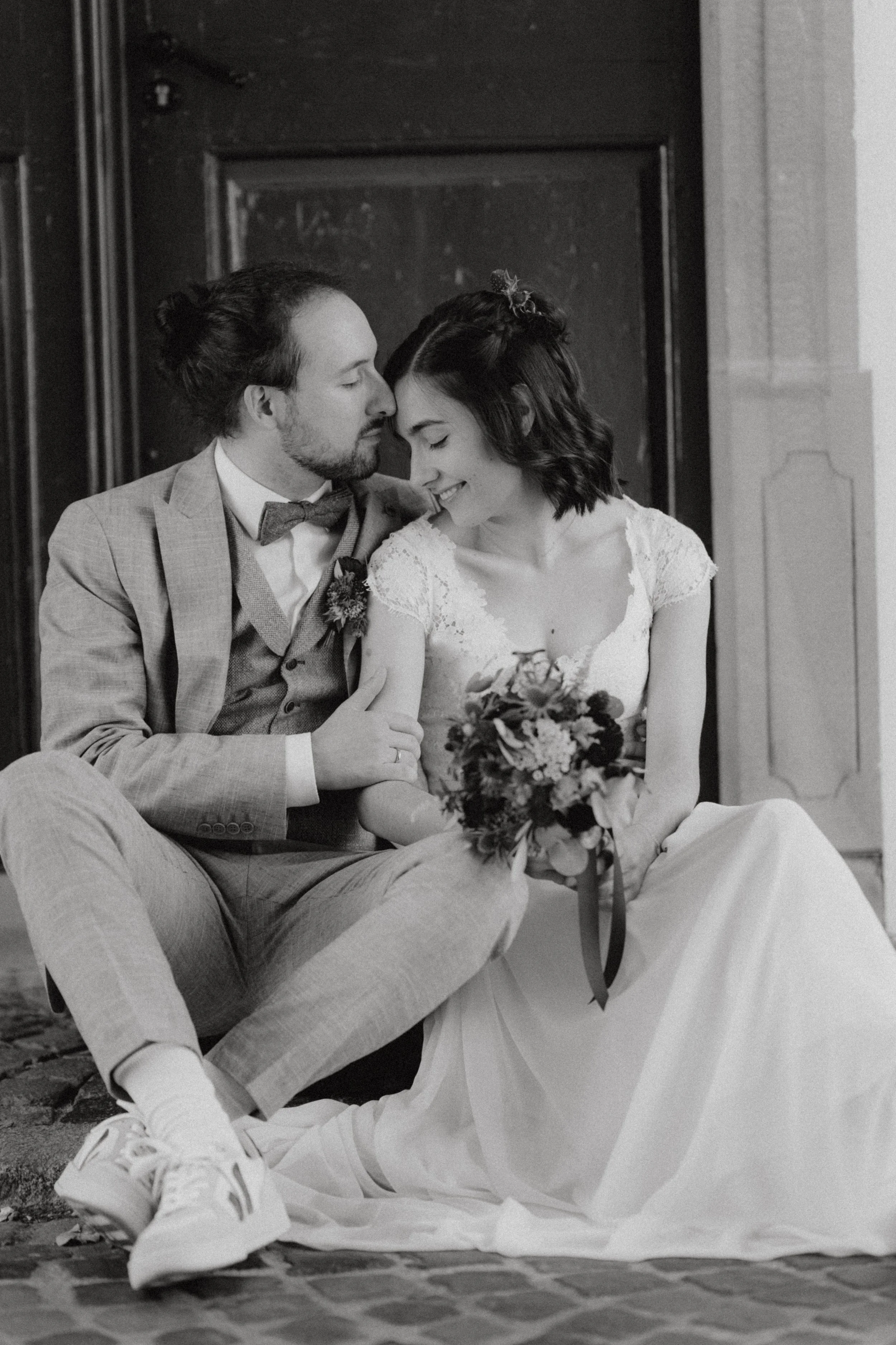 Hochzeitspaar, dass vor einer Tür sitzt und die Zweisamkeit genießt