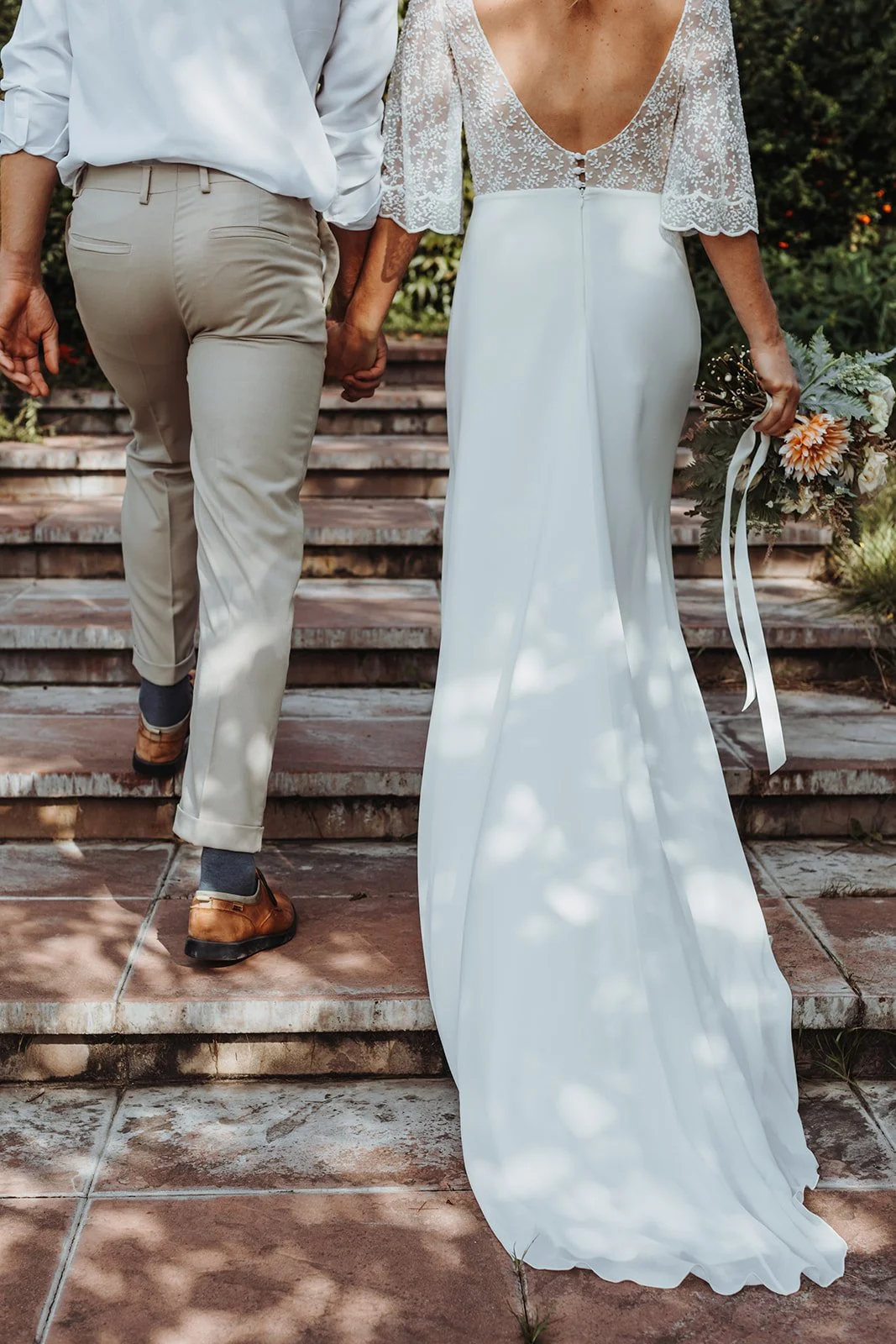 Hochzeitspaar wie es eine Treppe hinauf läuft