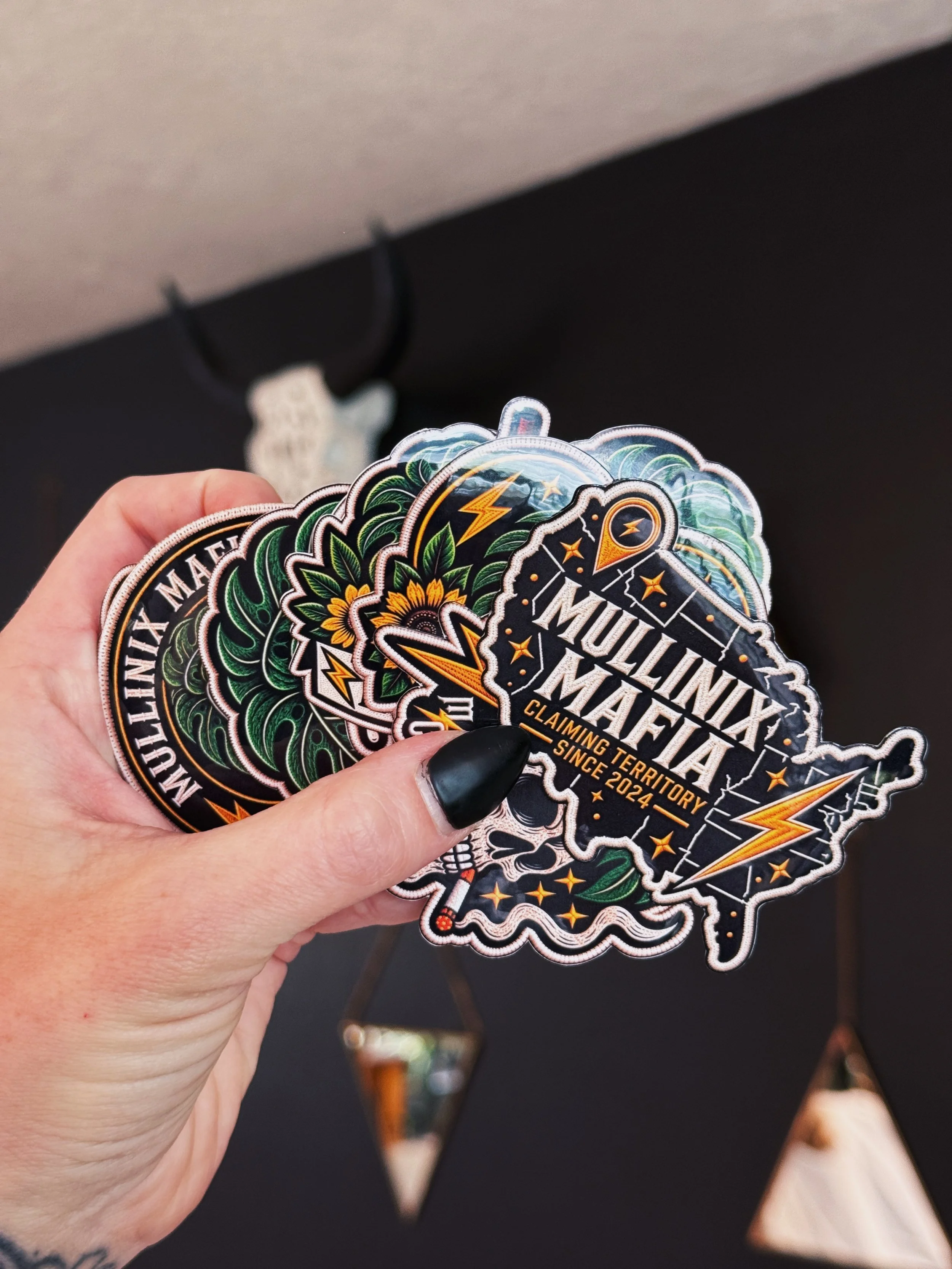 Mullinix Mafia sticker pack held in hand featuring nationwide map, skull, monstera and lightning bolt vinyl stickers