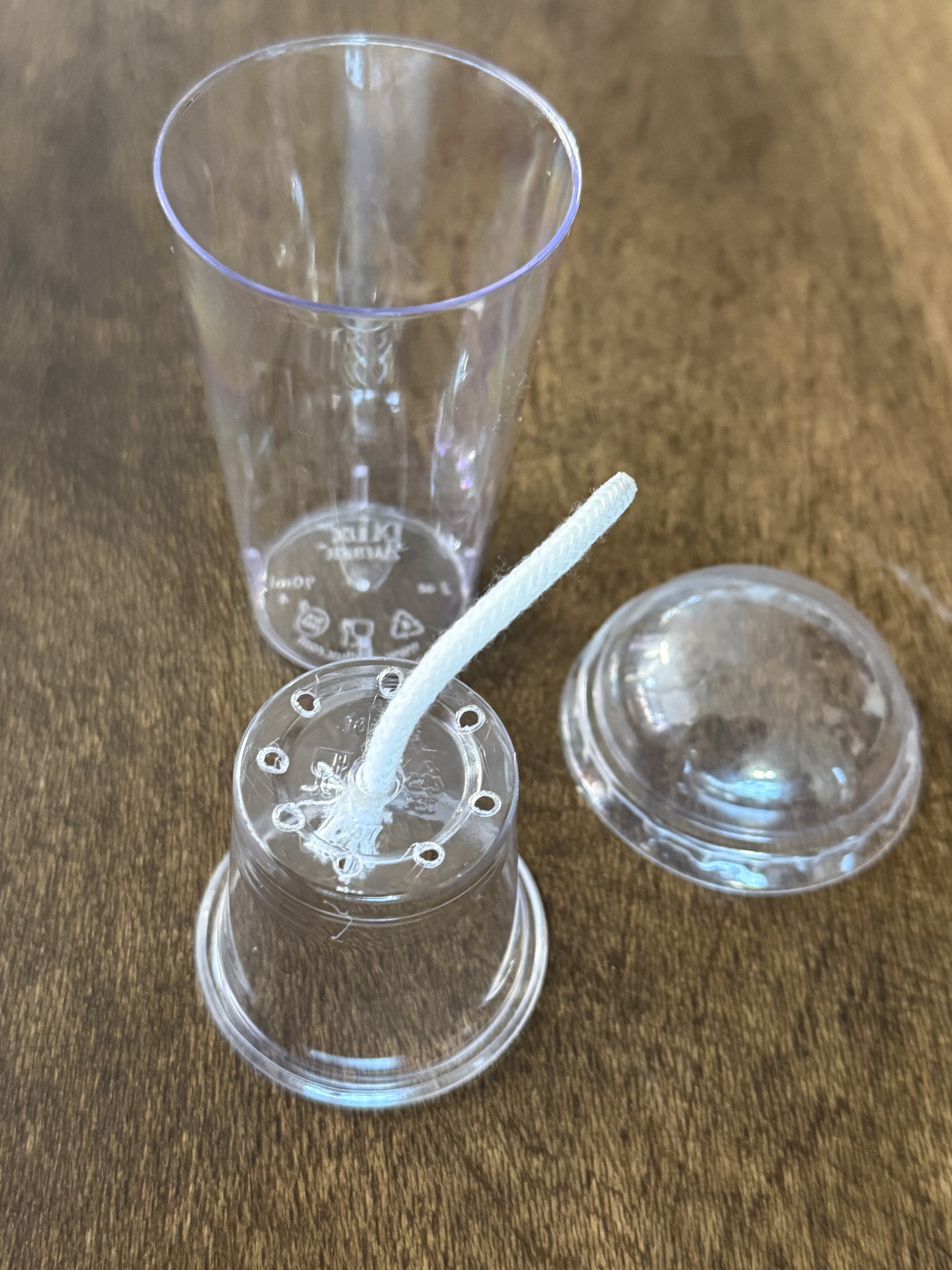 Disassembled self-watering corm cup showing inner cup, reservoir, wick, and dome