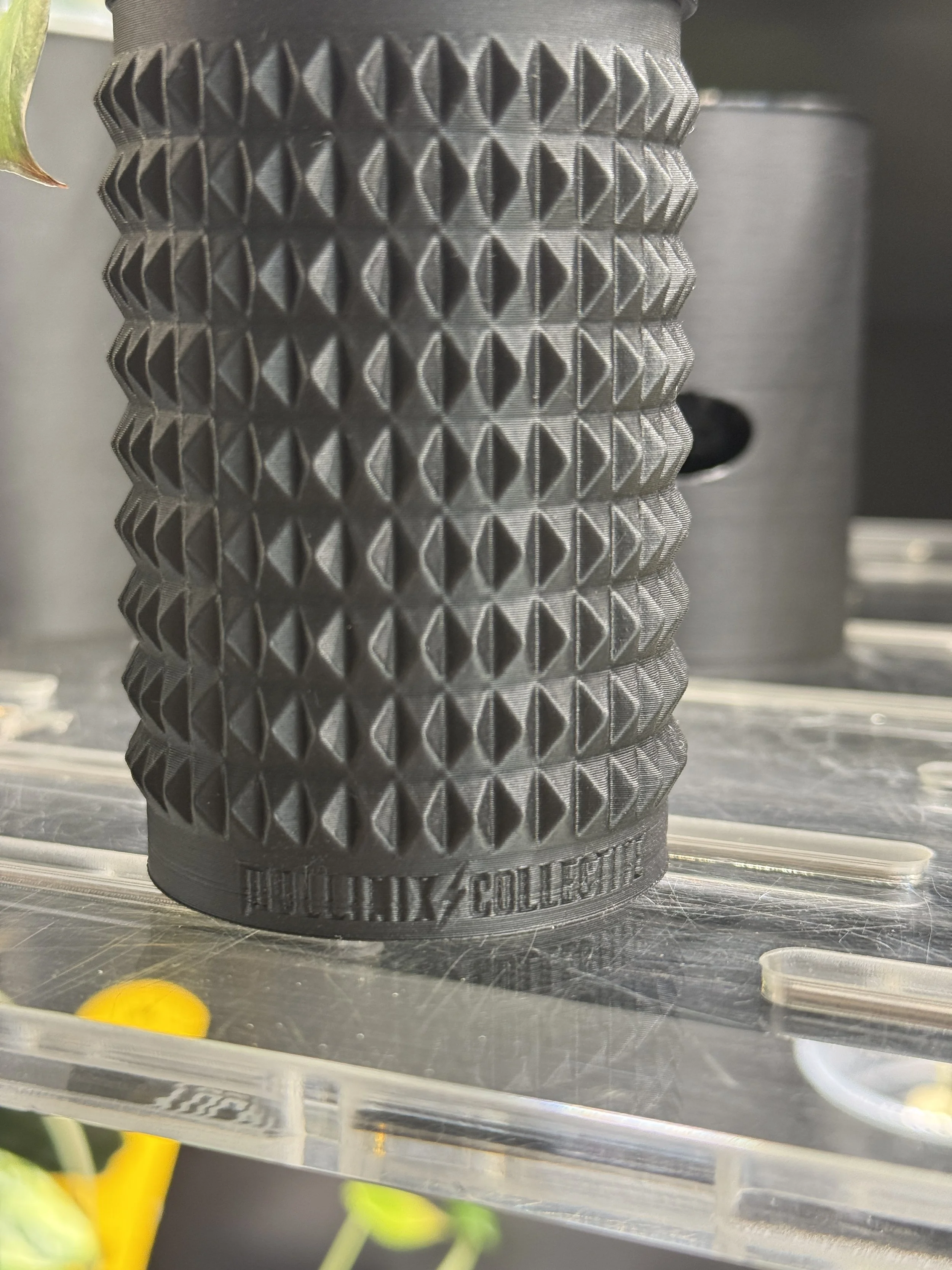 Detailed texture view of black spikey 3D printed cache cup with Mullinix Collective logo.
