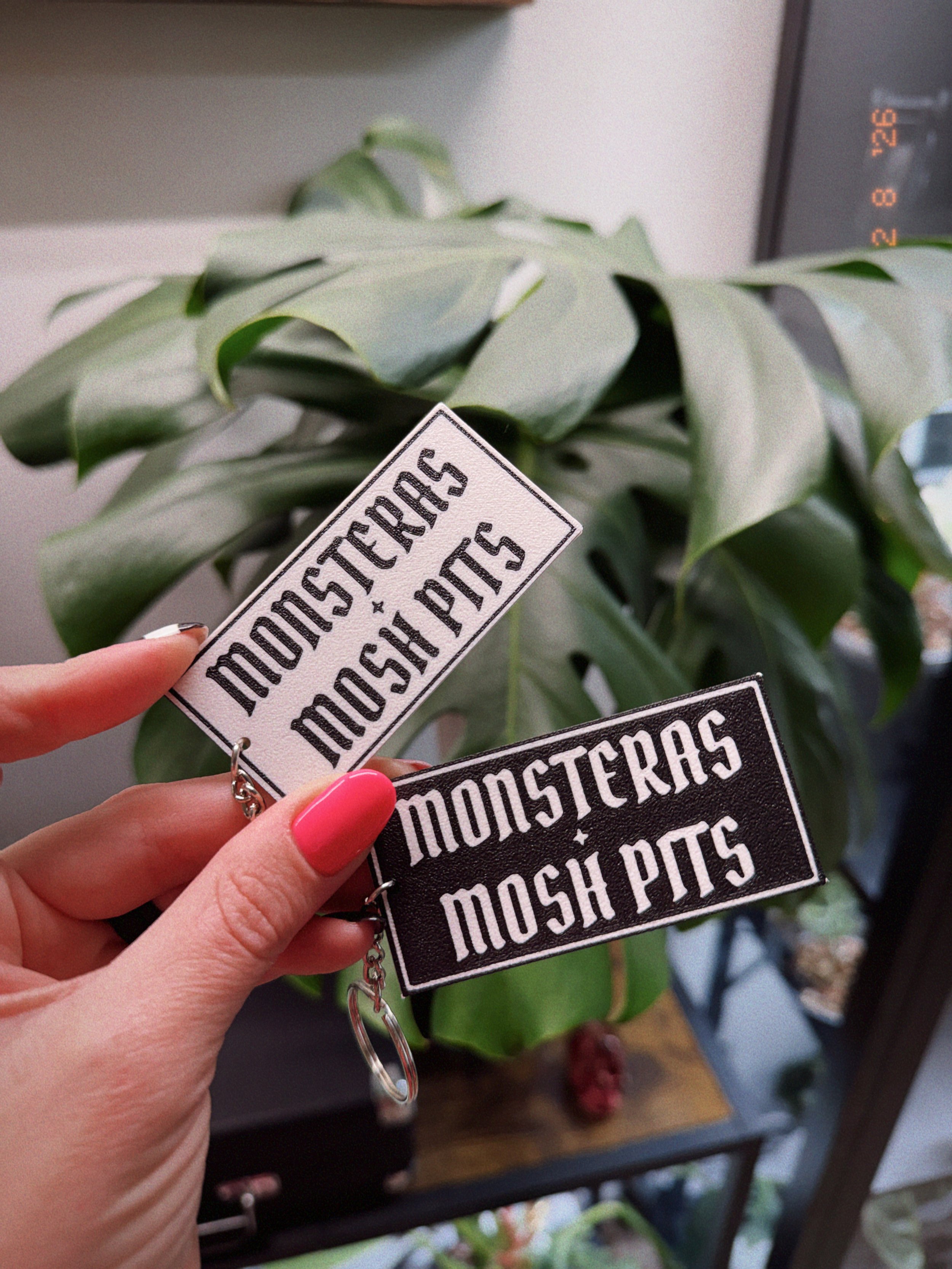 Close-up of Monsteras + Mosh Pits keychains in black and white showing textured 3D printed finish.