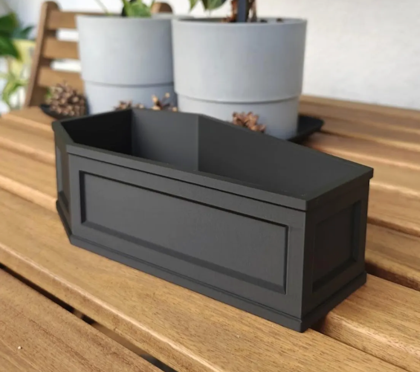Angled side view of empty black coffin planter highlighting beveled edges and panel design.