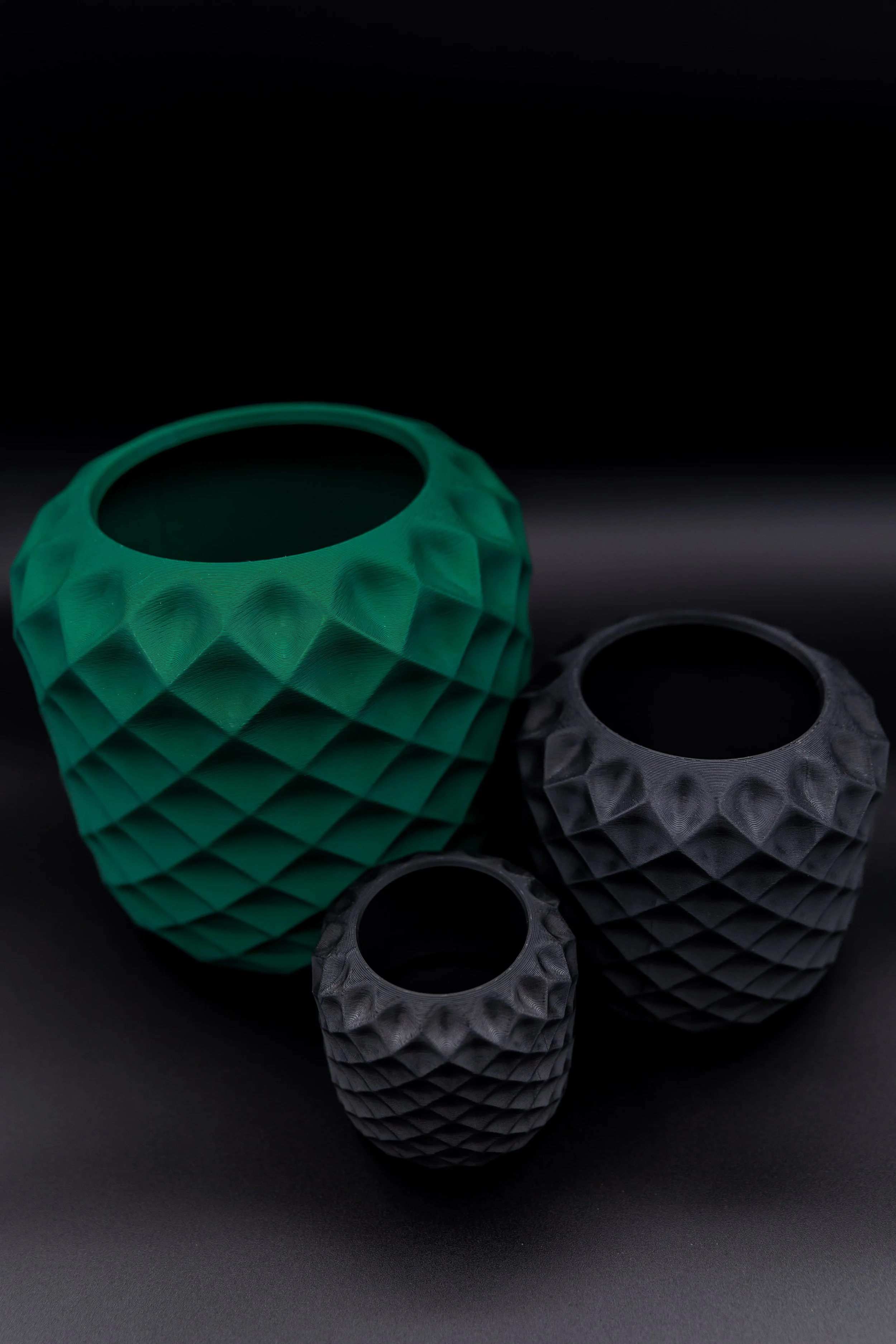 Group of three Shlie Planters in black and green, various sizes displayed on matte black backdrop.