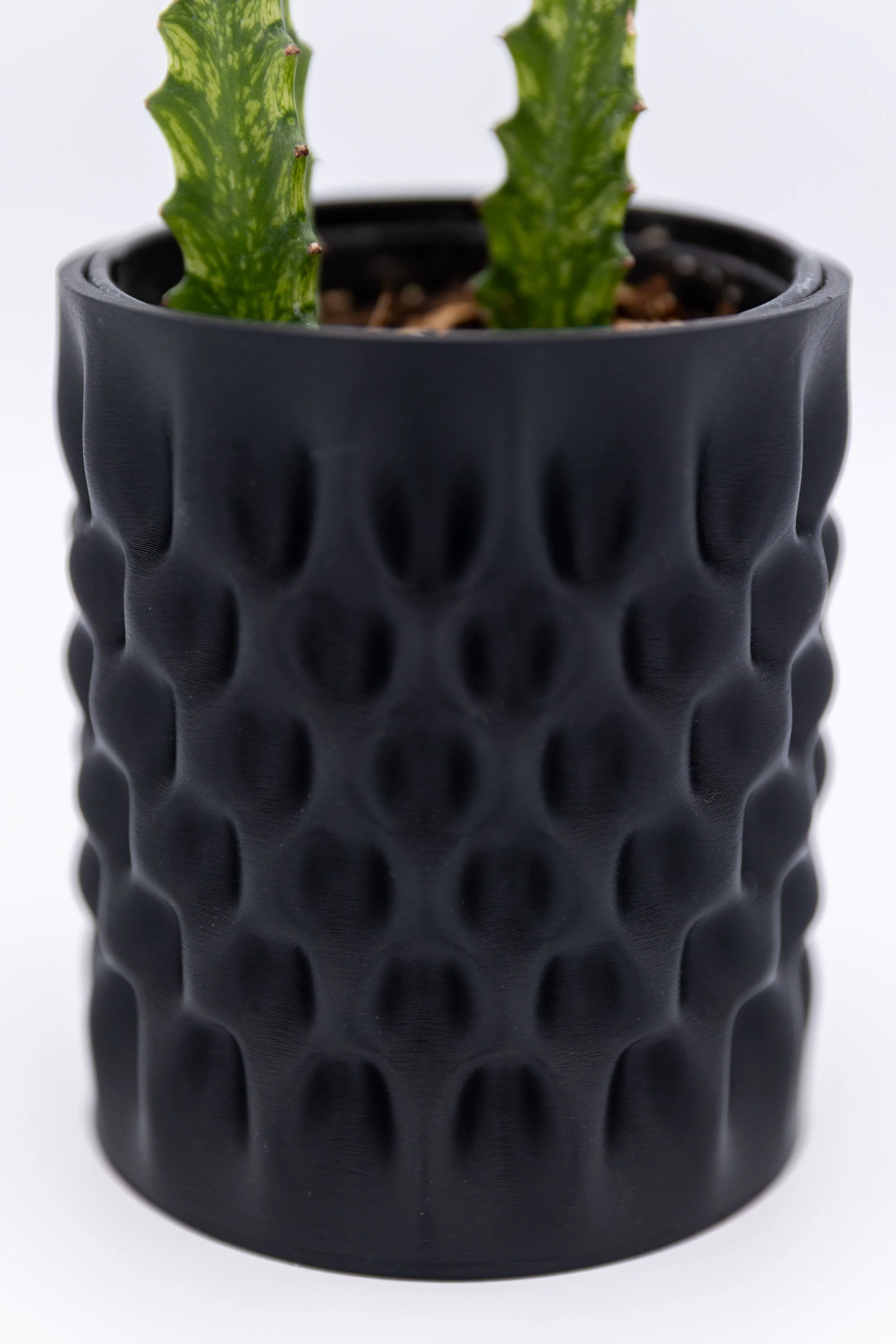 Close-up detail of the Undertow Planter showing the textured, wave-like pattern on the matte black 3D printed surface.