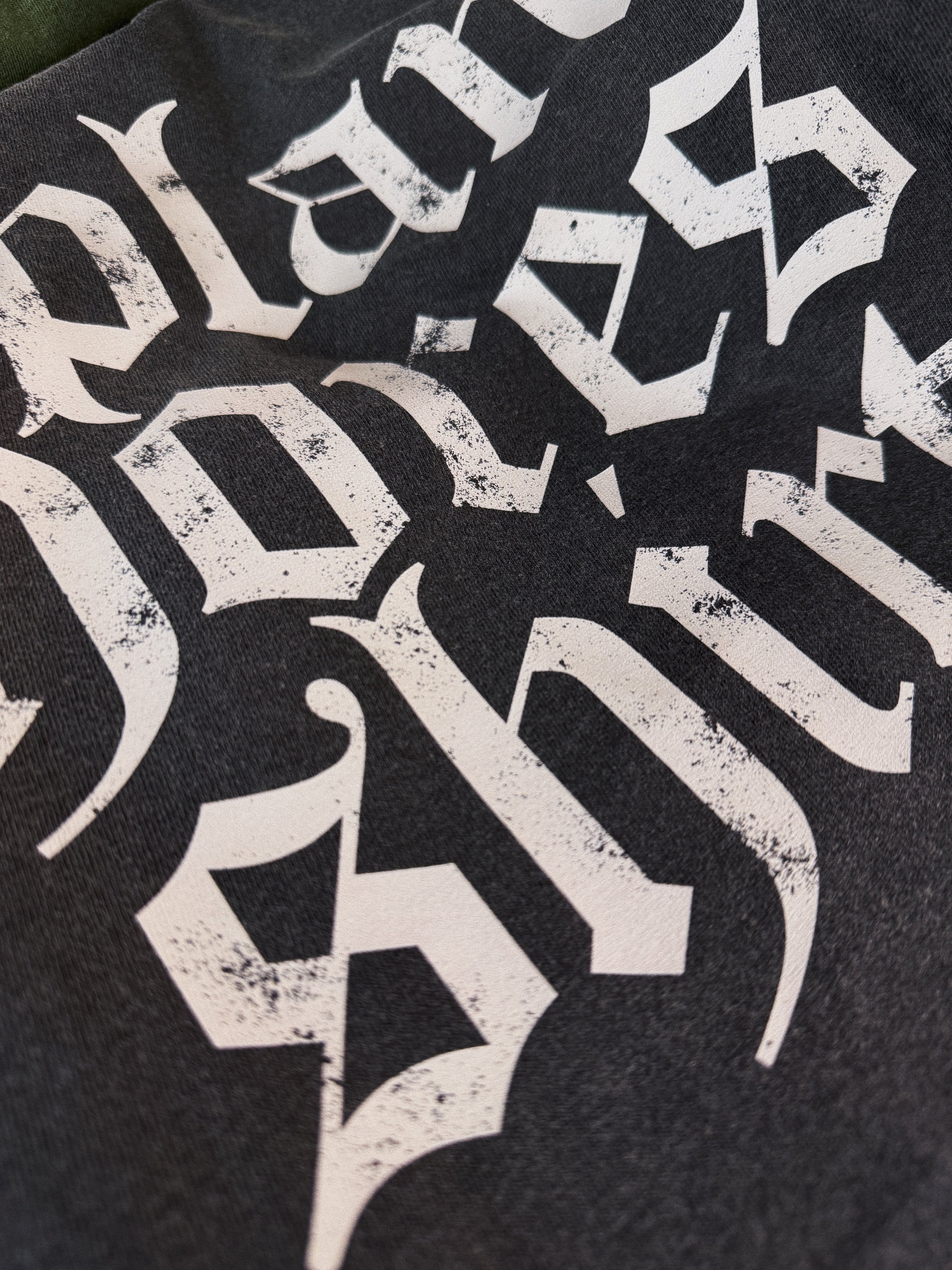 Close-up of distressed gothic "Plant Chores Shirt" graphic printed on charcoal Comfort Colors t-shirt